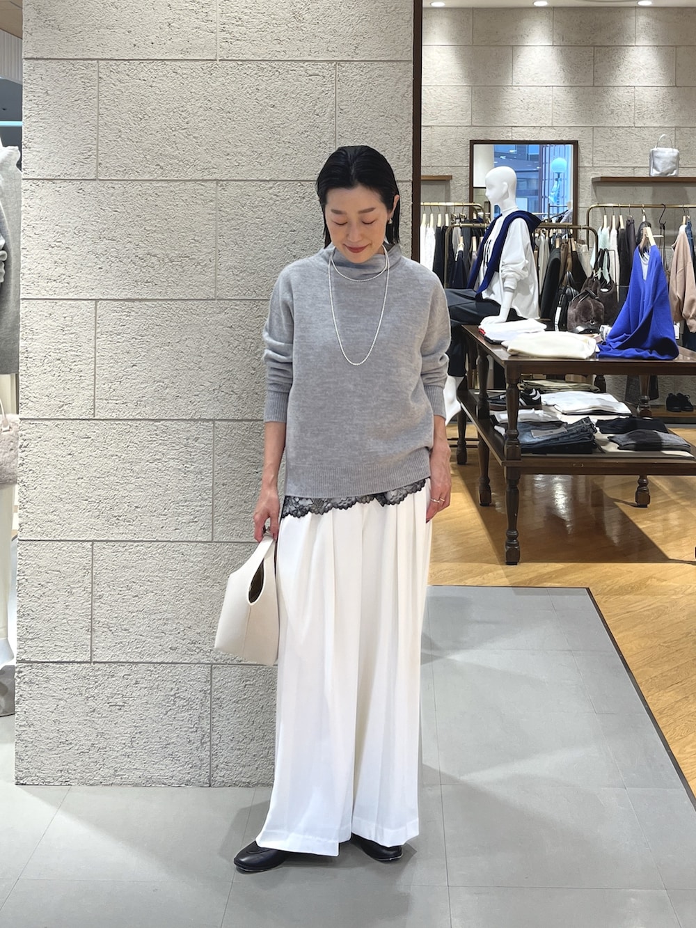 グレー系のニット/セーター、ブラック系のキャミソール、ホワイト系のスラックスを着用したレディースの冬コーディネートの2枚目の写真