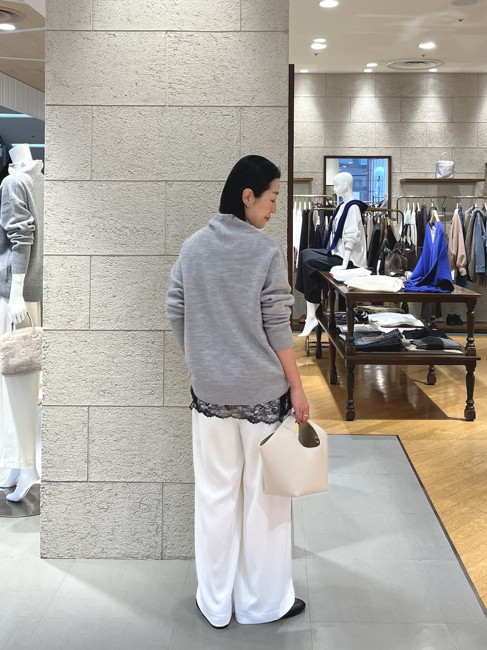 グレー系のニット/セーター、ブラック系のキャミソール、ホワイト系のスラックスを着用したレディースの冬コーディネートの4枚目の写真