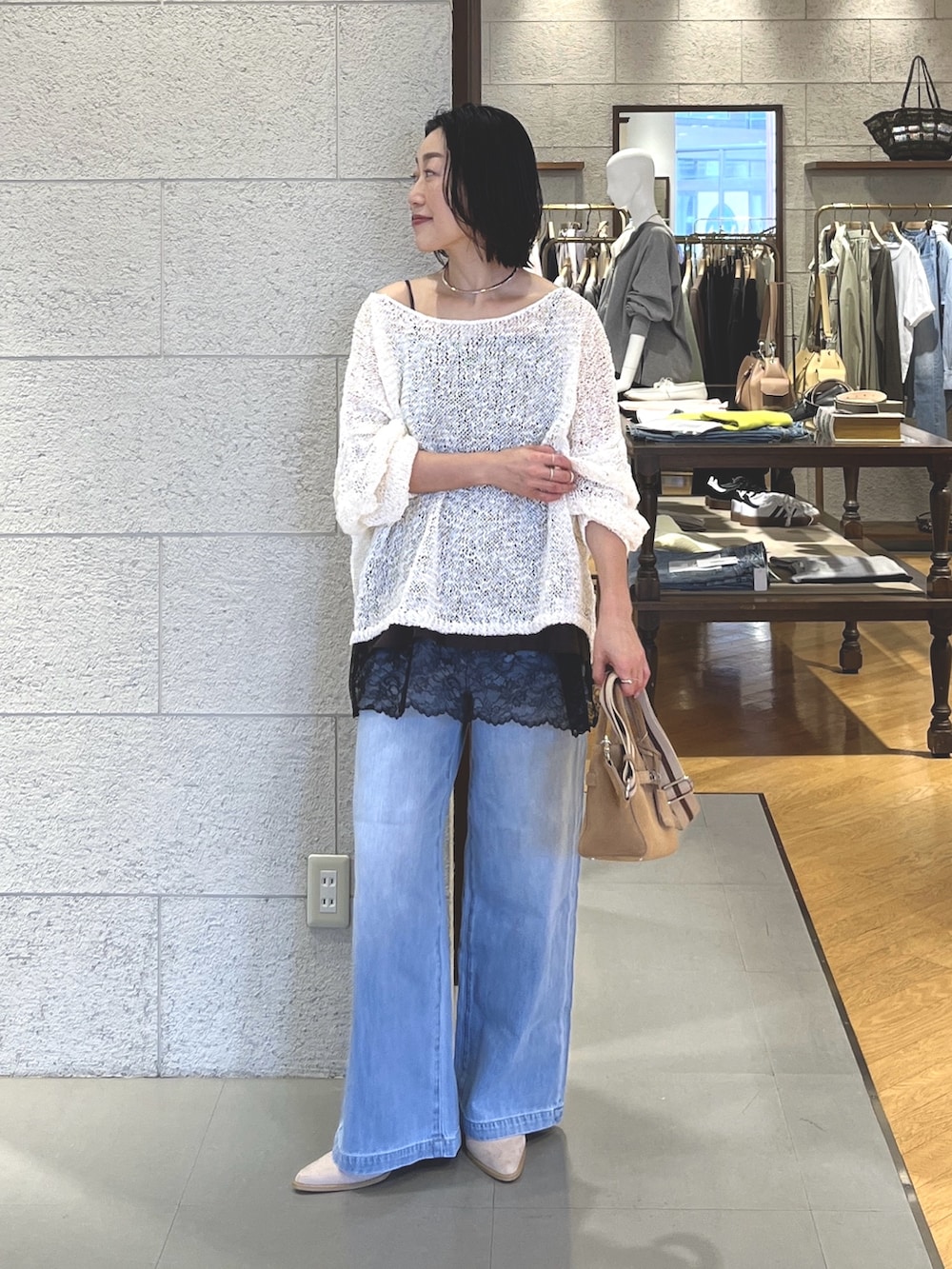 ホワイト系のニット/セーター、ブラウン系のキャミソール、ブルー系のデニムパンツを着用したレディースの春コーディネートの2枚目の写真