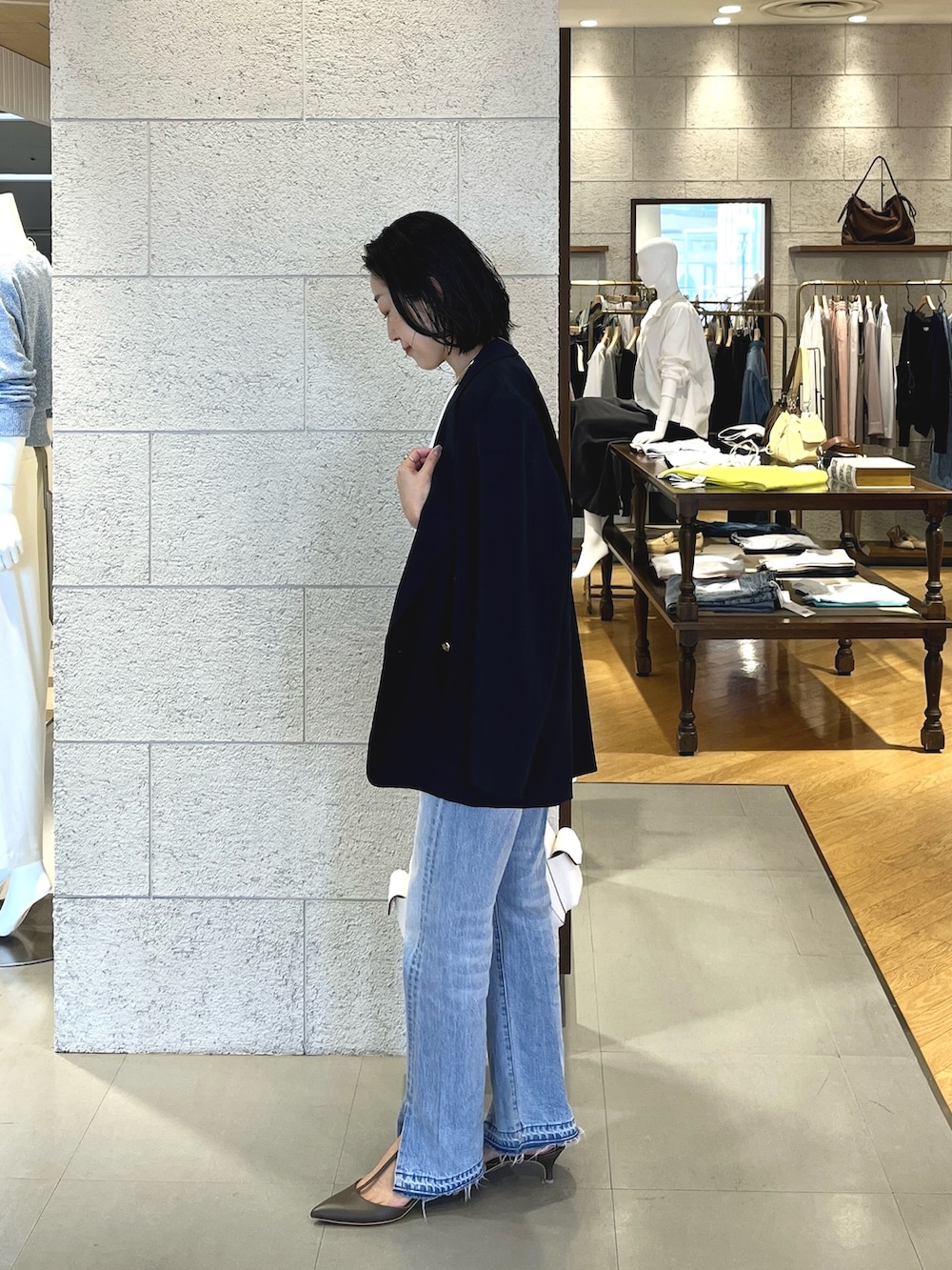 ブルー系のデニムパンツ、グレー系のその他シューズ、ホワイト系のショルダーバッグを着用したレディースの春コーディネートの3枚目の写真