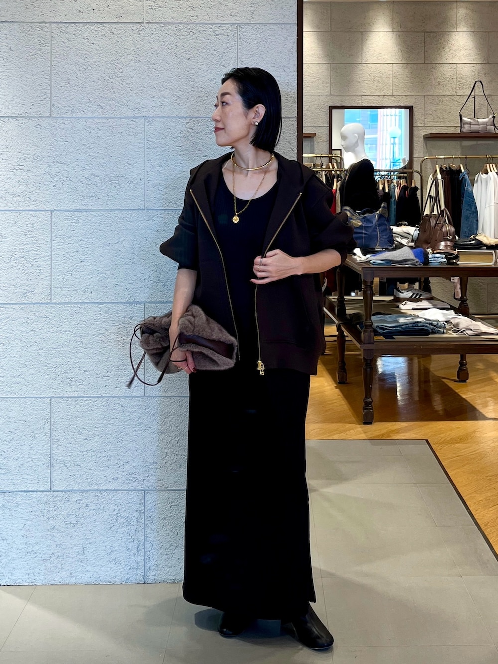 ブラウン系のハンドバッグ、ブラウン系のパーカー、ブラック系のワンピースを着用したレディースの秋コーディネートの2枚目の写真