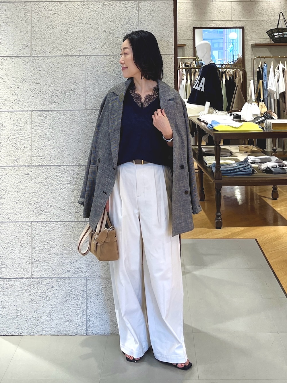 ブルー系のニット/セーター、ブラック系のテーラードジャケット、ホワイト系のチノパンツを着用したレディースの春コーディネートの2枚目の写真