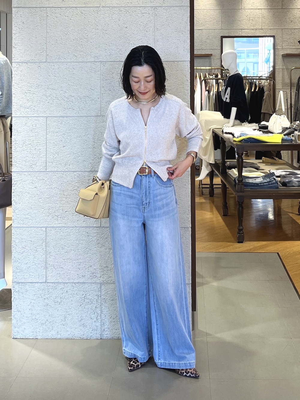 ベージュ系のその他シューズ、ベージュ系のショルダーバッグ、ブルー系のデニムパンツを着用したレディースの春コーディネートの2枚目の写真