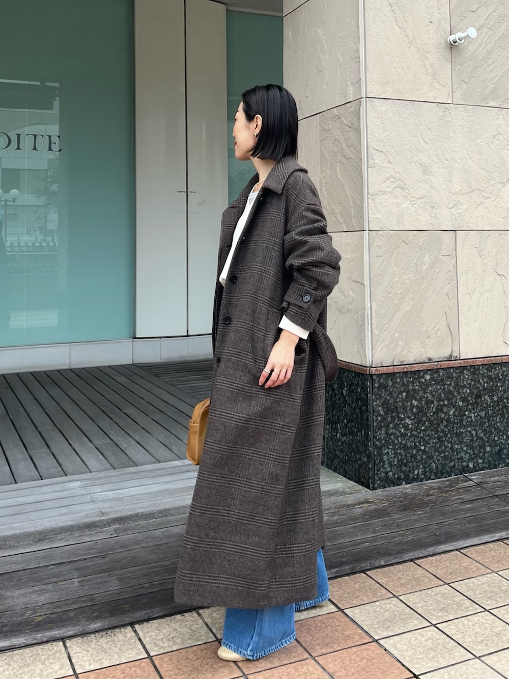 ブルー系のデニムパンツ、イエロー系のボストンバッグ、ベージュ系のブーツを着用したレディースの秋コーディネートの4枚目の写真