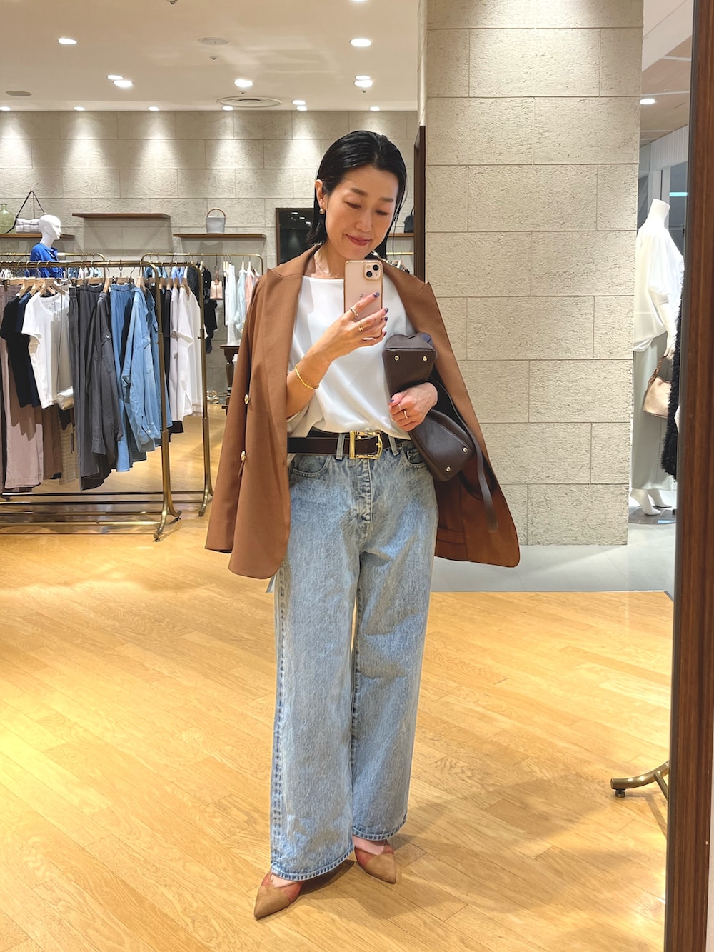 ブルー系のデニムパンツ、ブラウン系のパンプス、ブラウン系のショルダーバッグを着用したレディースの夏コーディネートの4枚目の写真