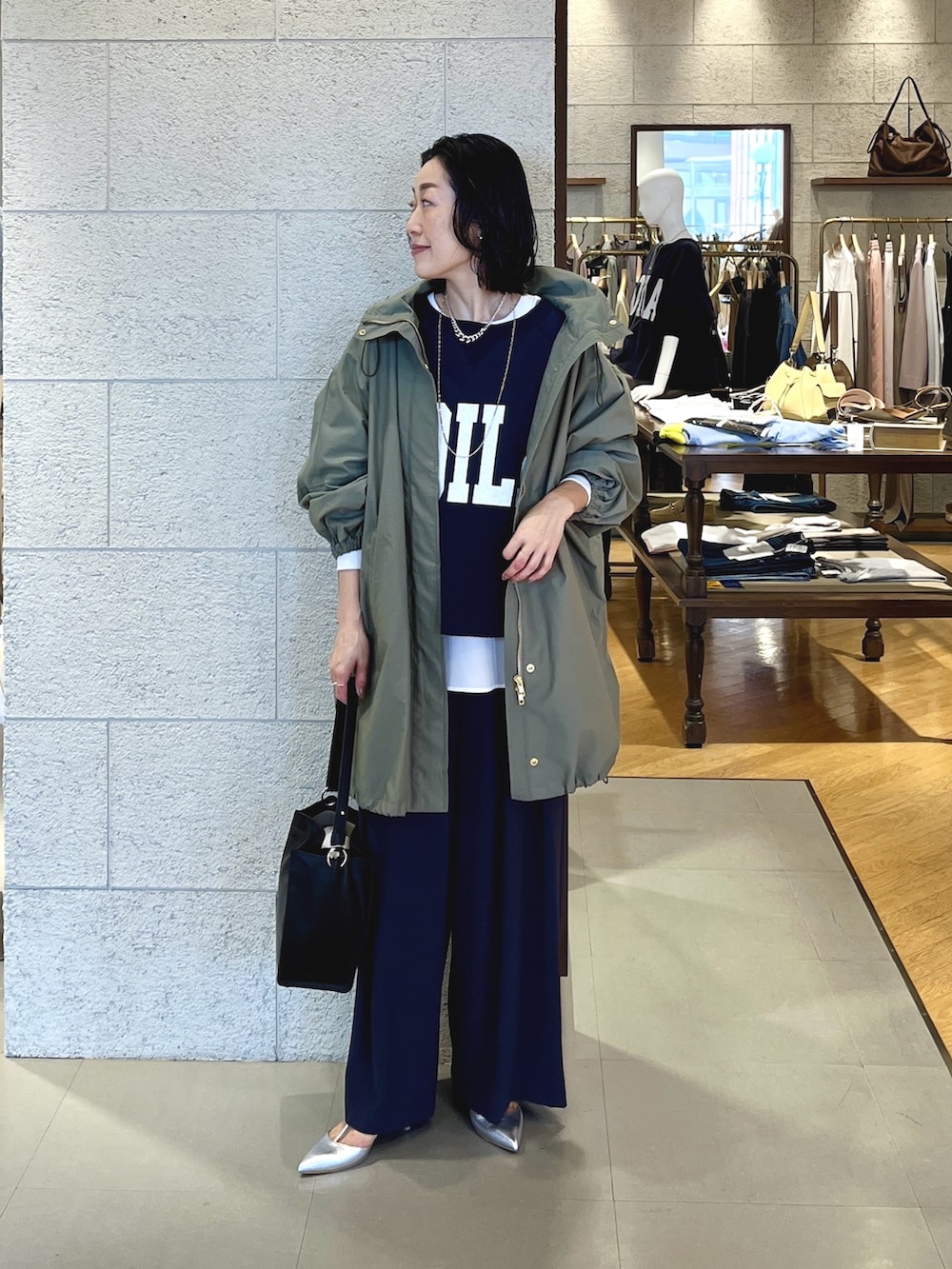 グレー系のスラックス、ブラック系のショルダーバッグ、シルバー系のその他シューズを着用したレディースの春コーディネートの2枚目の写真