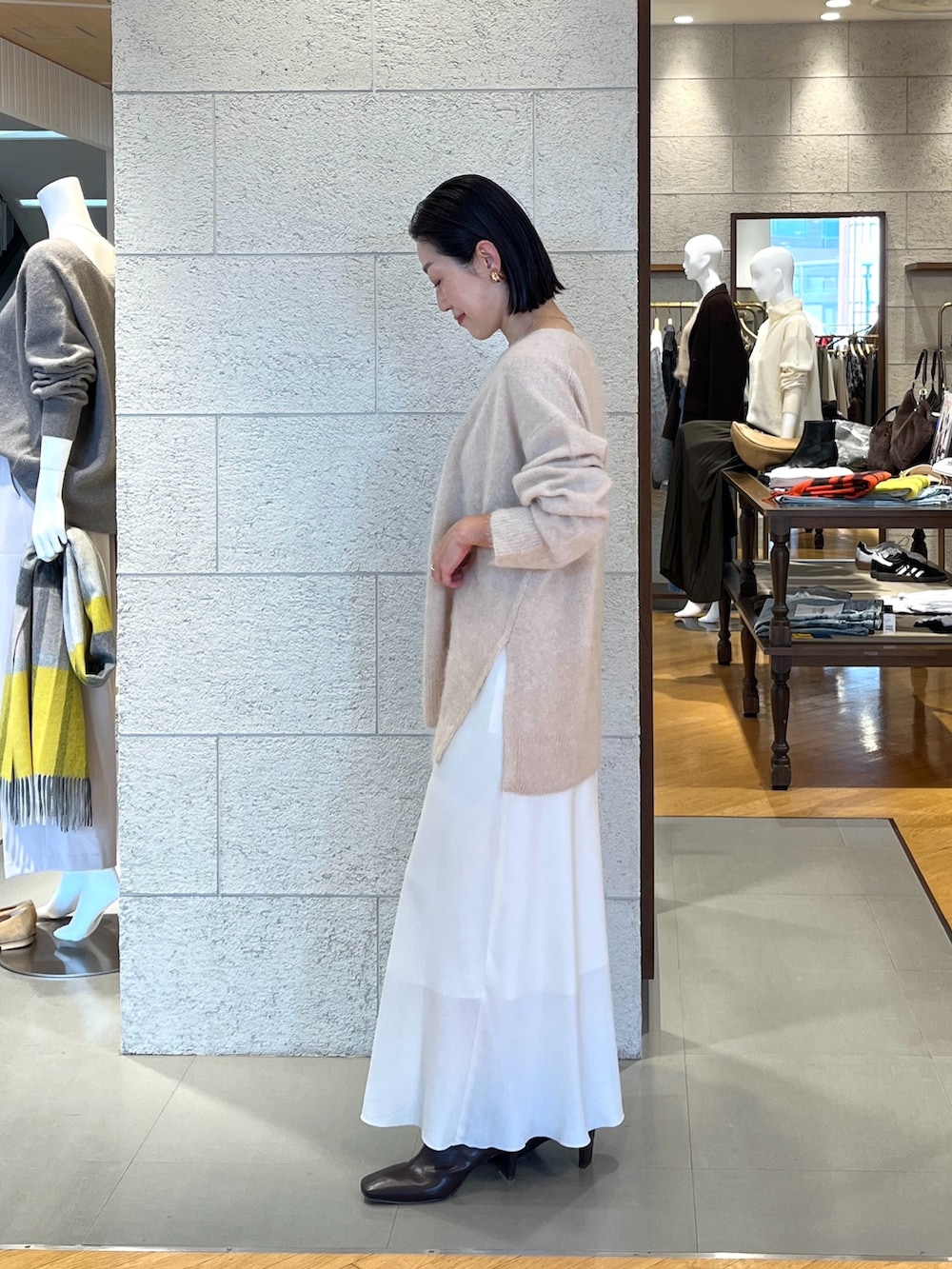 ホワイト系のスカート、ベージュ系のニット/セーター、ブラウン系のブーツを着用したレディースの秋コーディネートの3枚目の写真