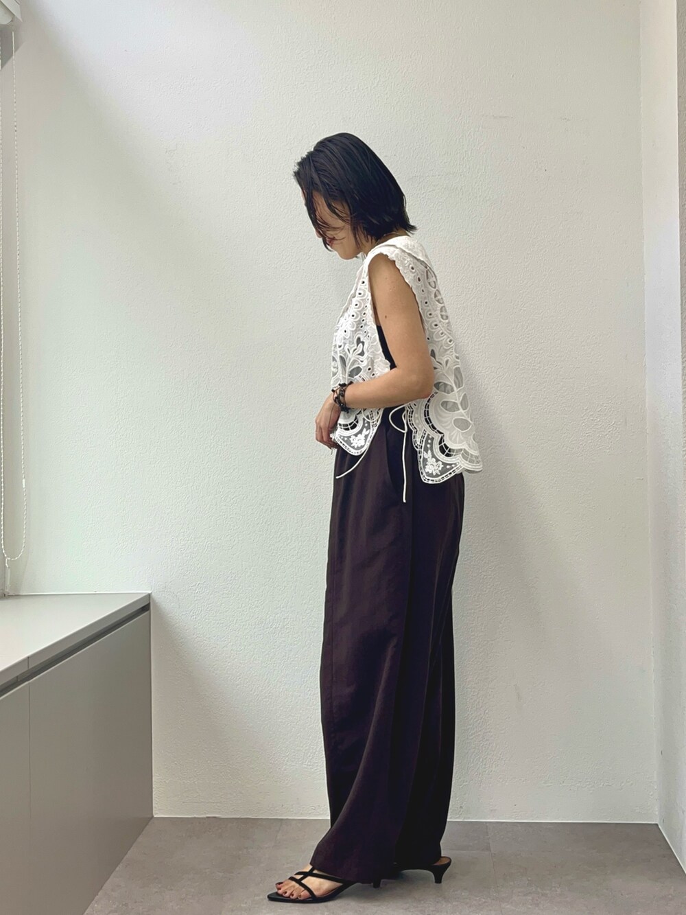 ブラウン系のその他パンツ、ブラウン系のサンダル、ホワイト系のベストを着用したレディースの夏コーディネートの3枚目の写真