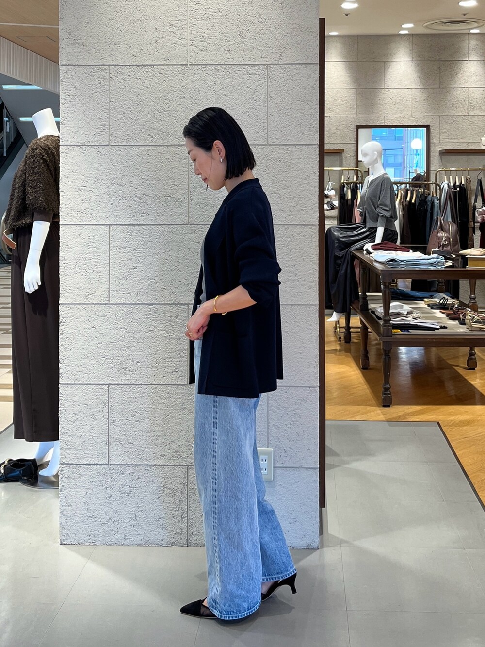 ブラック系のパンプス、ブルー系のテーラードジャケット、ブルー系のデニムパンツを着用したレディースの夏コーディネートの3枚目の写真