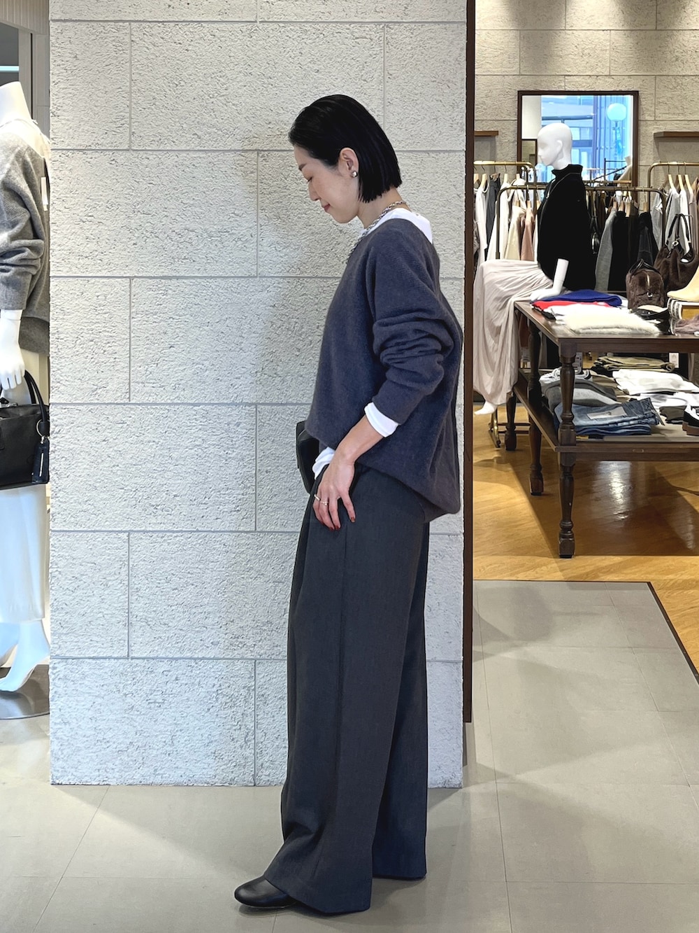 グレー系のニット/セーター、ホワイト系のTシャツ/カットソー、グレー系のスラックスを着用したレディースの冬コーディネートの3枚目の写真