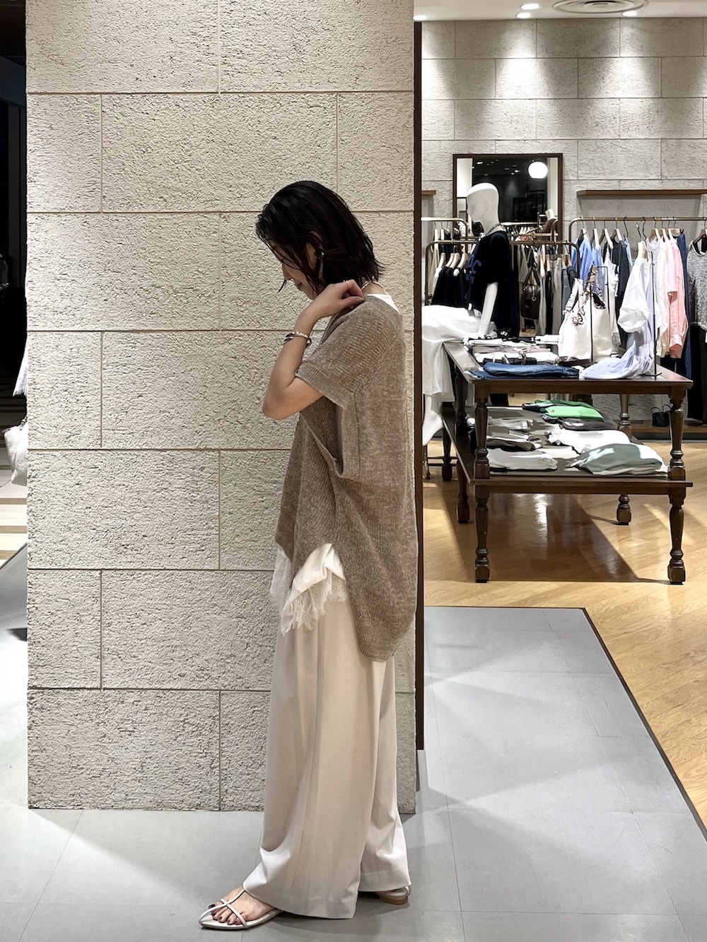 ベージュ系のサンダル、ブラウン系のボストンバッグ、ベージュ系のスラックスを着用したレディースの夏コーディネートの3枚目の写真