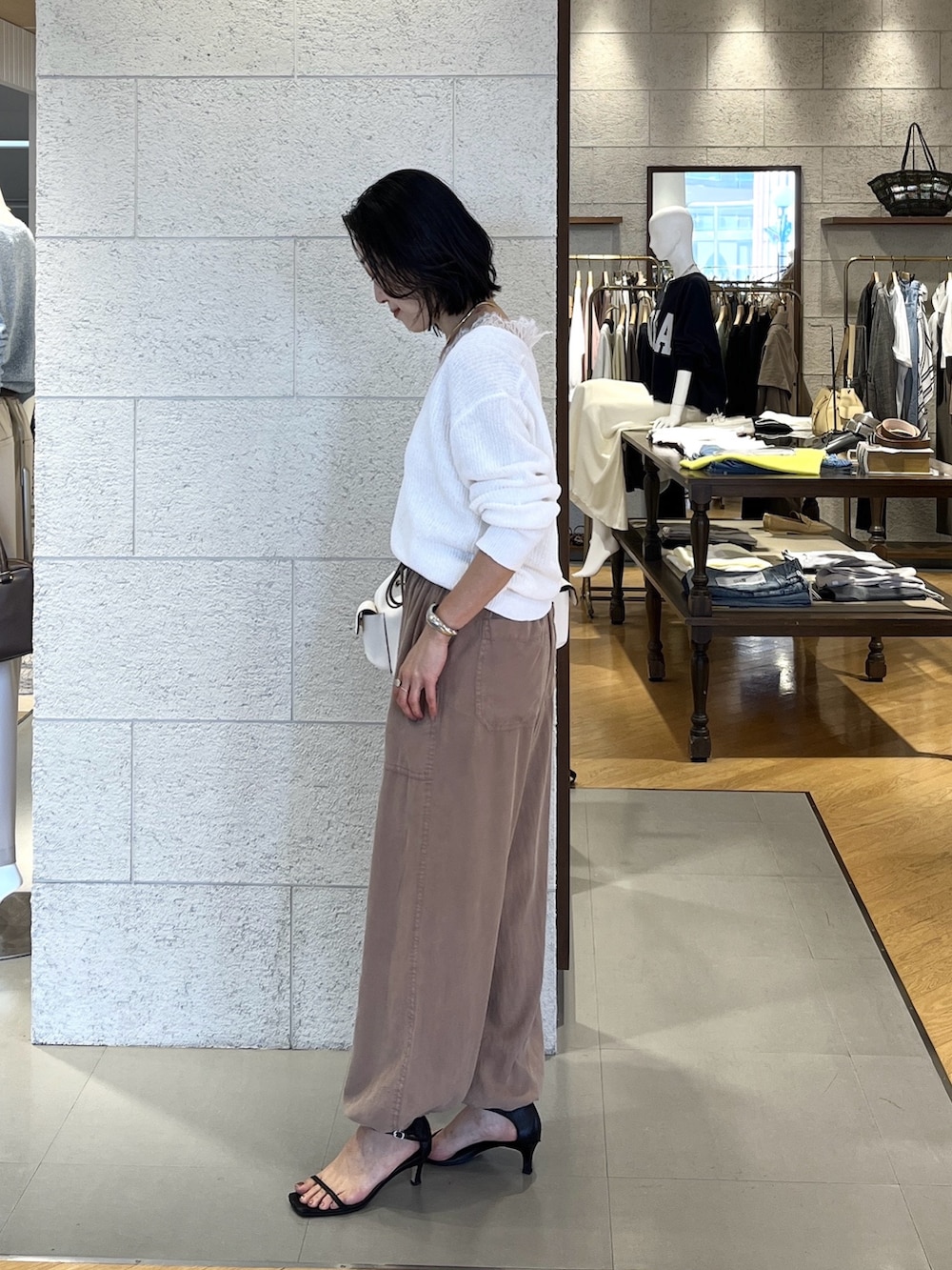 ホワイト系のショルダーバッグ、ホワイト系のニット/セーター、ブラウン系のその他パンツを着用したレディースの春コーディネートの2枚目の写真