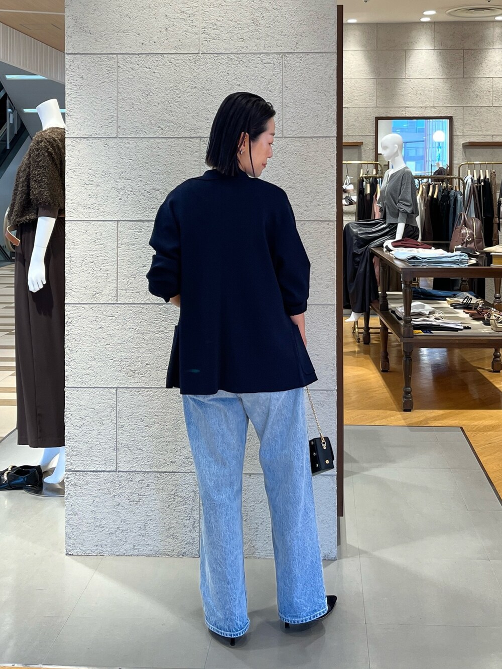 ブラック系のパンプス、ブルー系のテーラードジャケット、ブルー系のデニムパンツを着用したレディースの夏コーディネートの4枚目の写真