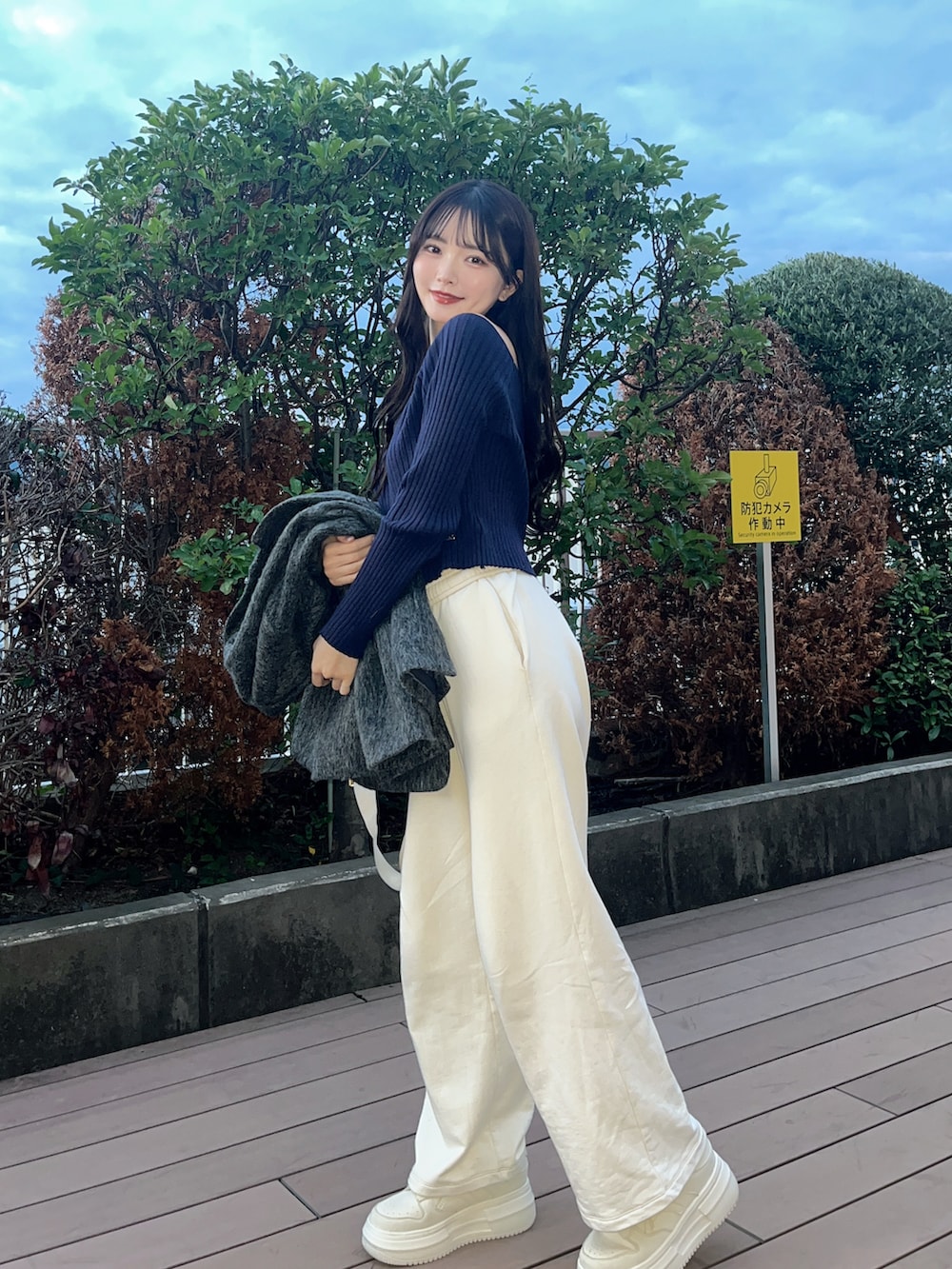 グレー系のテーラードジャケット、ブルー系のニット/セーター、ホワイト系のスニーカーを着用したレディースの秋コーディネートの2枚目の写真