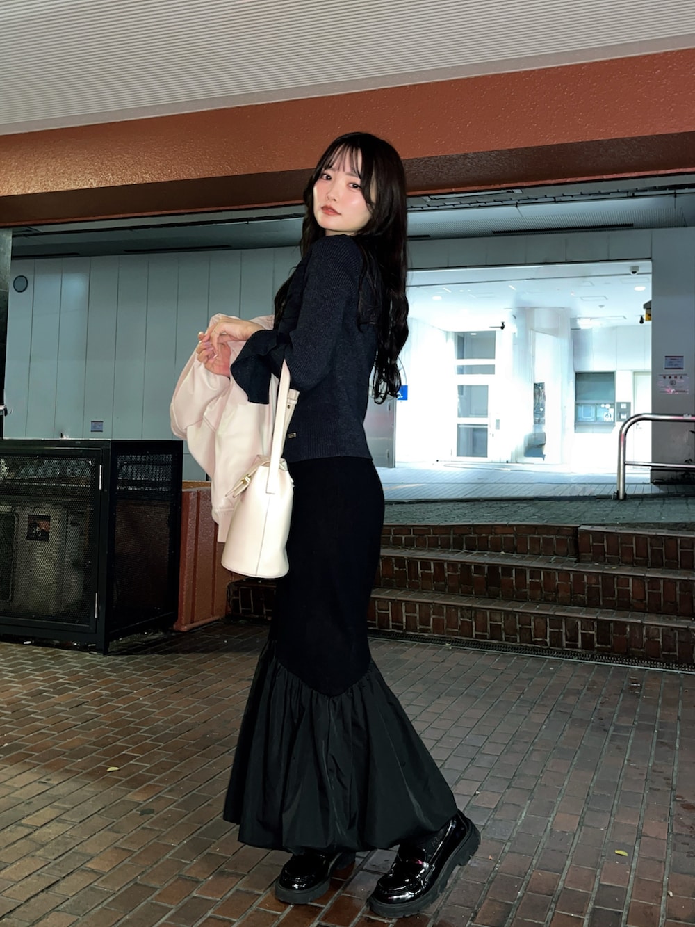 ベージュ系のライダースジャケット、ブラック系のスカート、ブラック系のローファーを着用したレディースの秋コーディネートの4枚目の写真