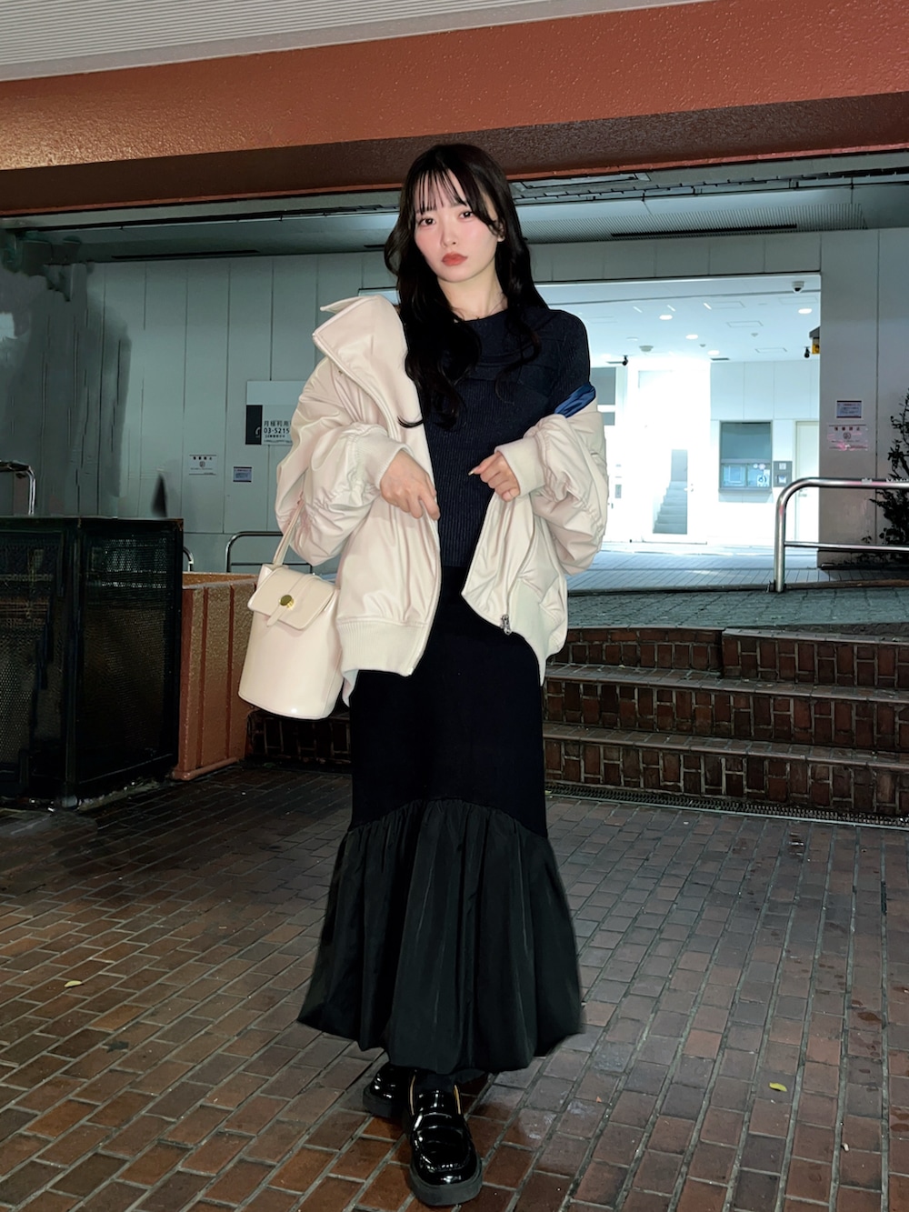 ベージュ系のライダースジャケット、ブラック系のスカート、ブラック系のローファーを着用したレディースの秋コーディネートの3枚目の写真