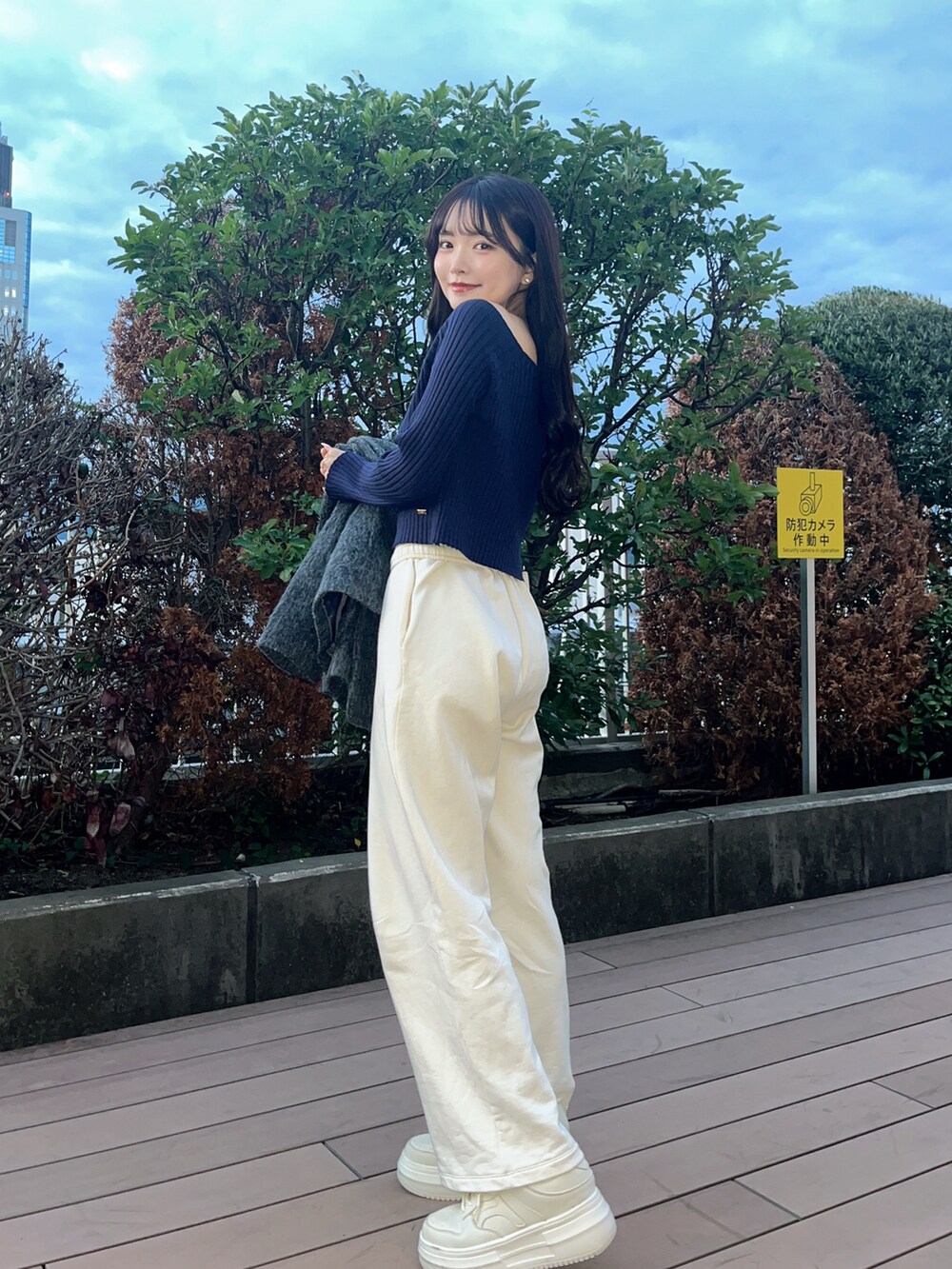 グレー系のテーラードジャケット、ブルー系のニット/セーター、ホワイト系のスニーカーを着用したレディースの秋コーディネートの4枚目の写真