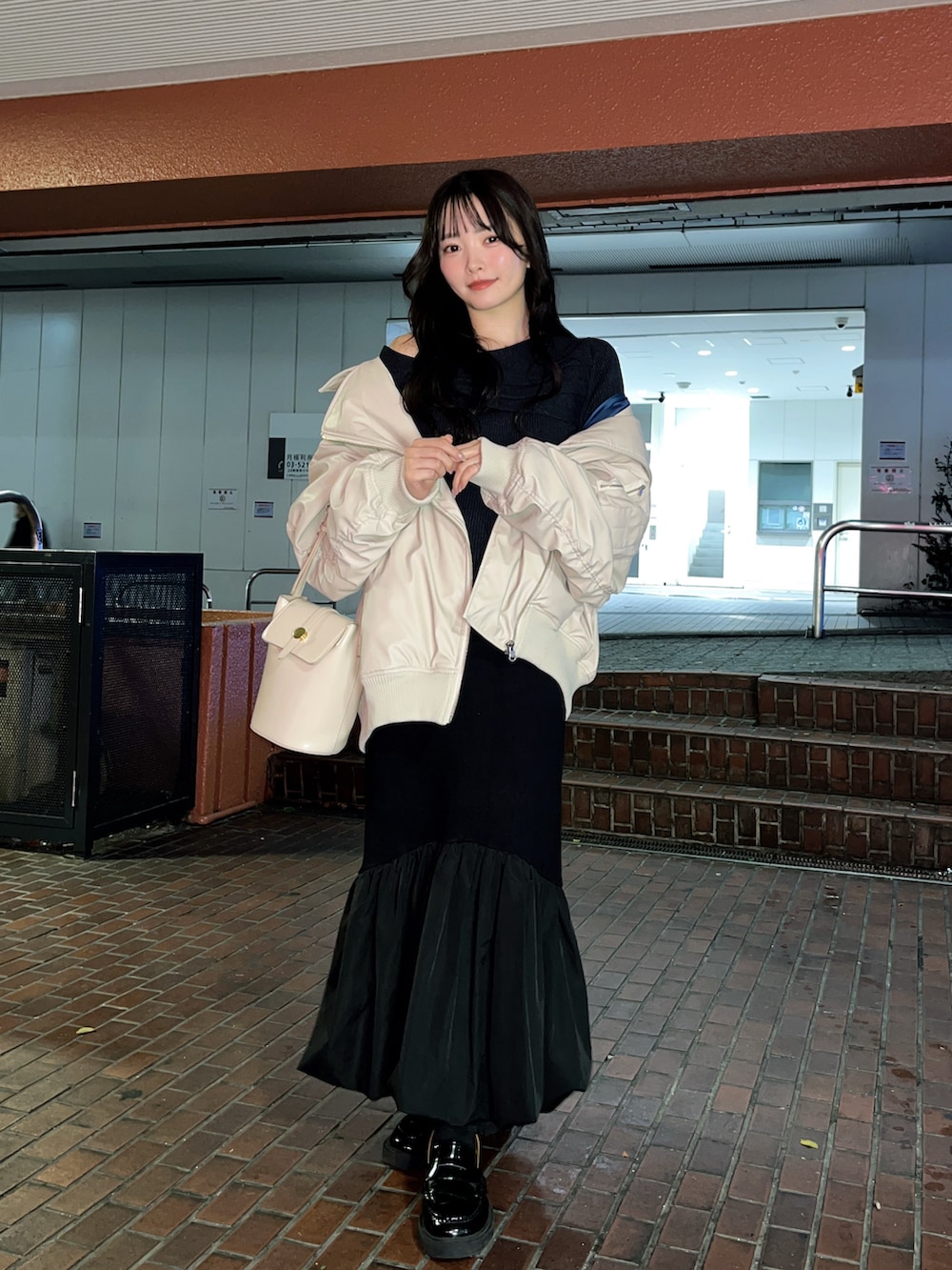 ベージュ系のライダースジャケット、ブラック系のスカート、ブラック系のローファーを着用したレディースの秋コーディネートの2枚目の写真