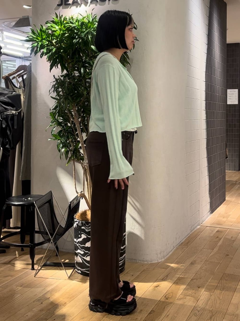 グリーン系のカーディガン/ボレロ、ブラウン系のデニムパンツ、ブラック系のサンダルを着用したレディースの夏コーディネートの4枚目の写真