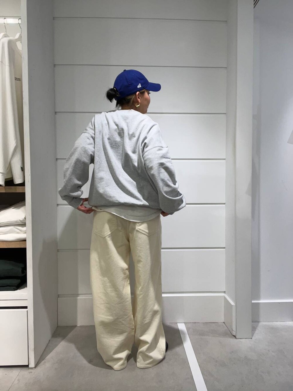 グレー系のスウェット、ホワイト系のその他パンツ、ブルー系のキャップを着用したレディースの秋コーディネートの3枚目の写真