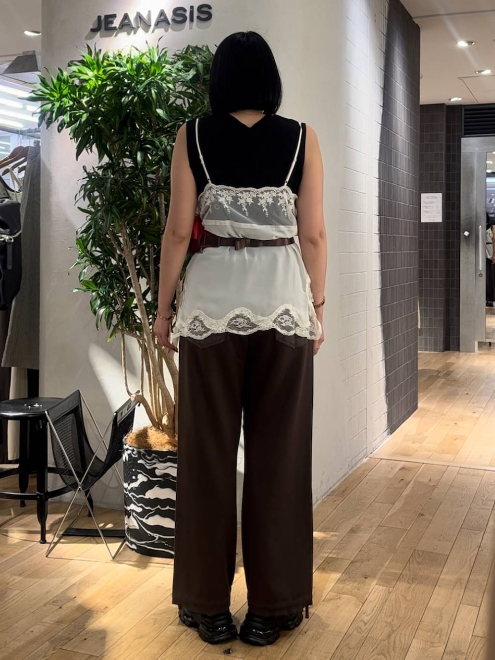 ホワイト系のキャミソール、ブラウン系のデニムパンツ、ブラック系のサンダルを着用したレディースの夏コーディネートの3枚目の写真