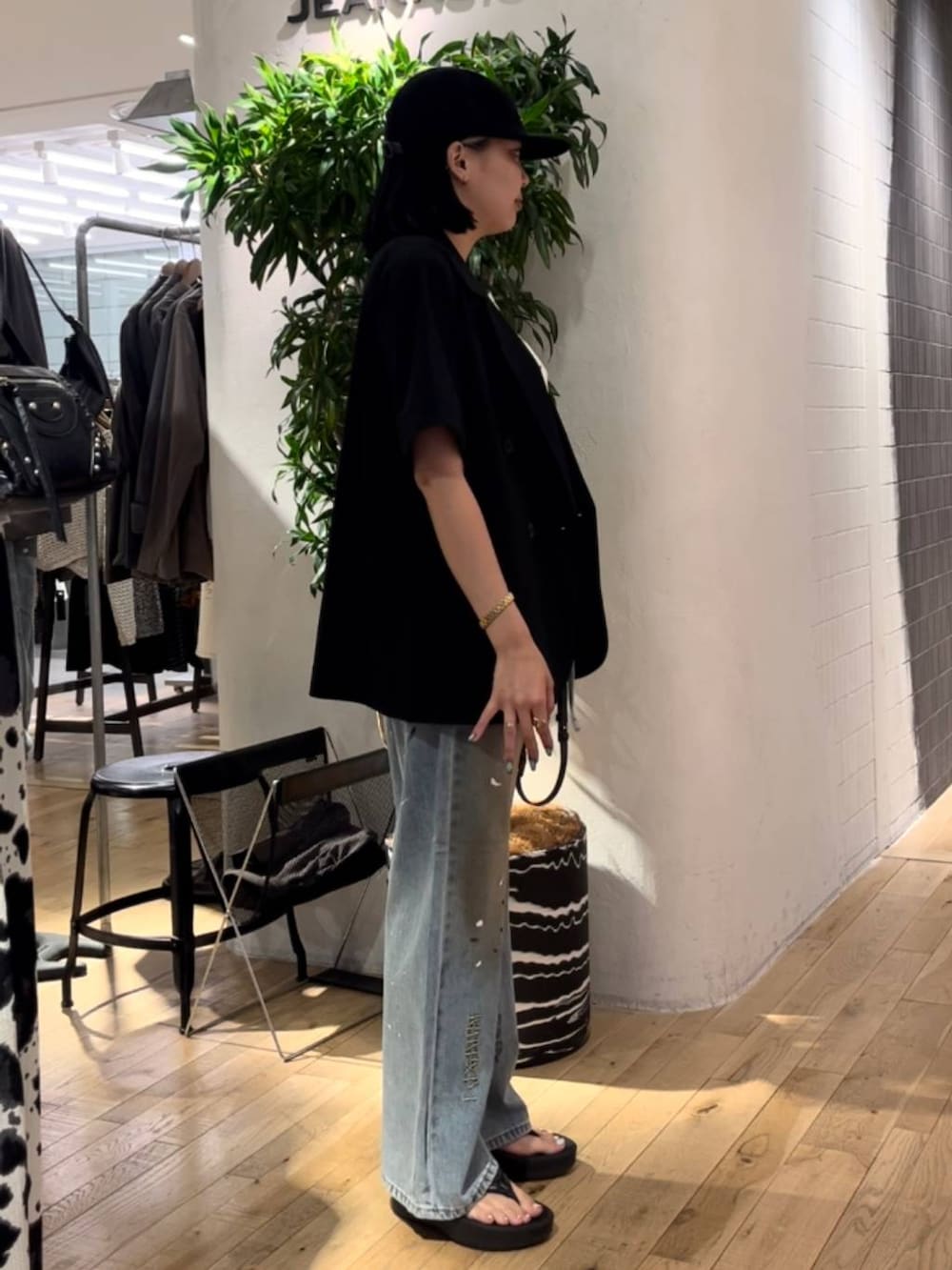 ブルー系のデニムパンツ、ホワイト系のタンクトップ、ブラック系のショルダーバッグを着用したレディースの夏コーディネートの4枚目の写真