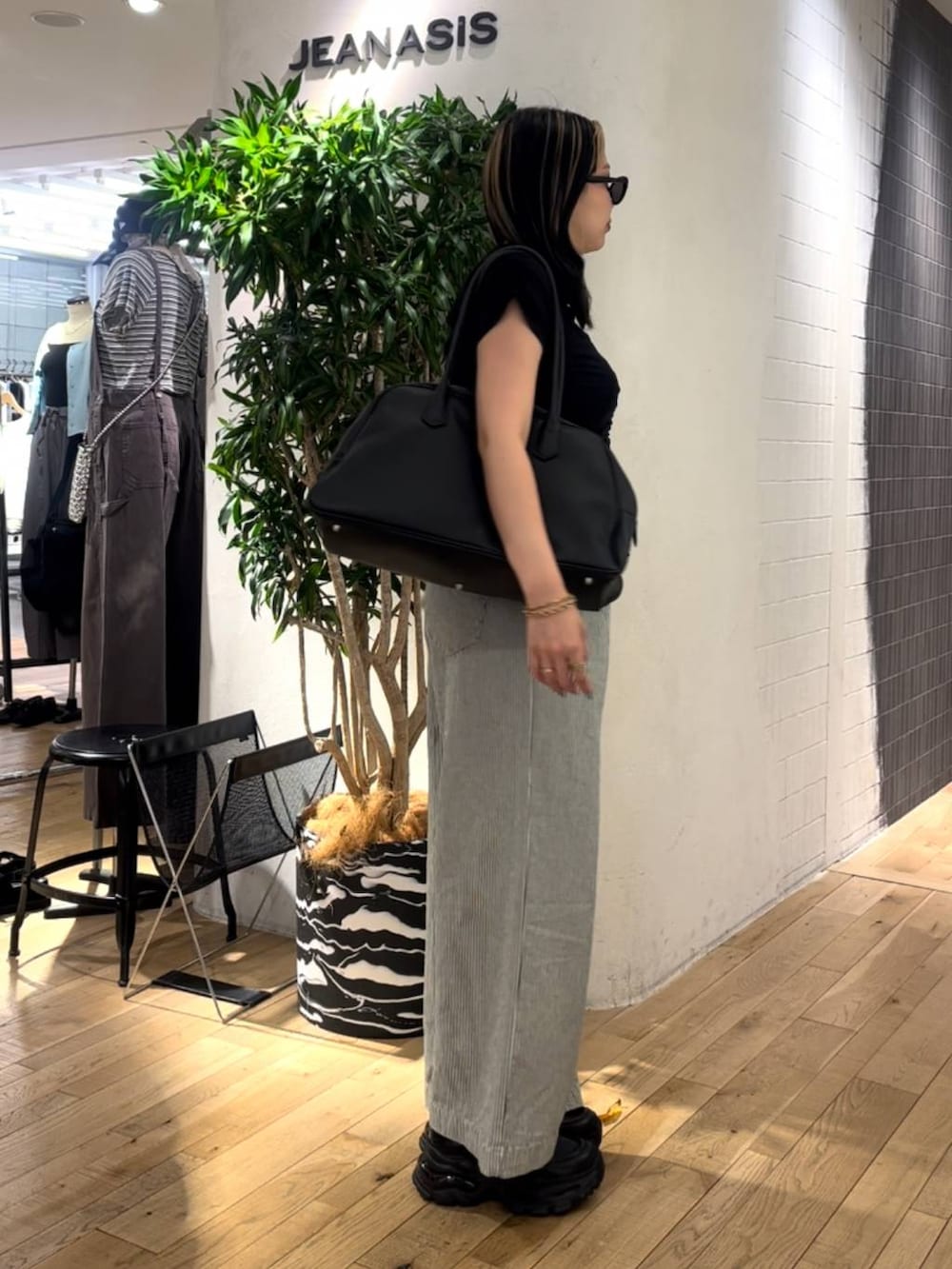 ブラック系のショルダーバッグ、ブラック系のローファー、ホワイト系のデニムパンツを着用したレディースの春コーディネートの4枚目の写真
