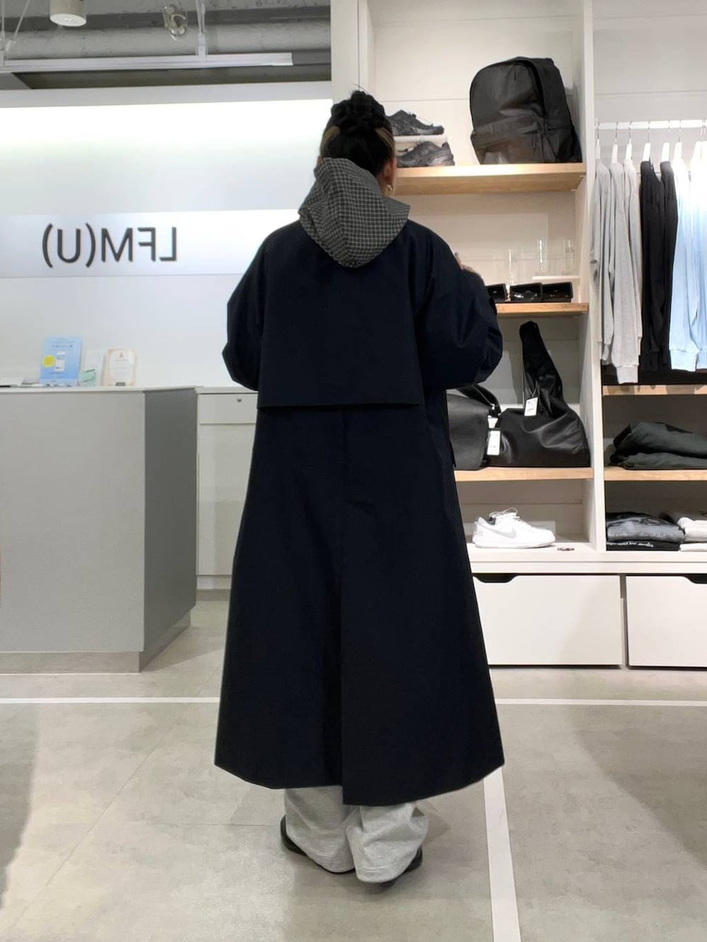 ブラック系のドレスシューズ、グレー系のスウェットパンツ、ブルー系のステンカラーコートを着用したレディースの春コーディネートの2枚目の写真