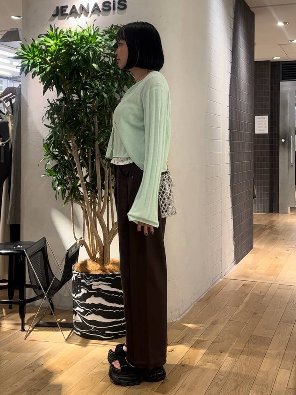 グリーン系のカーディガン/ボレロ、ブラウン系のデニムパンツ、ブラック系のサンダルを着用したレディースの夏コーディネートの2枚目の写真