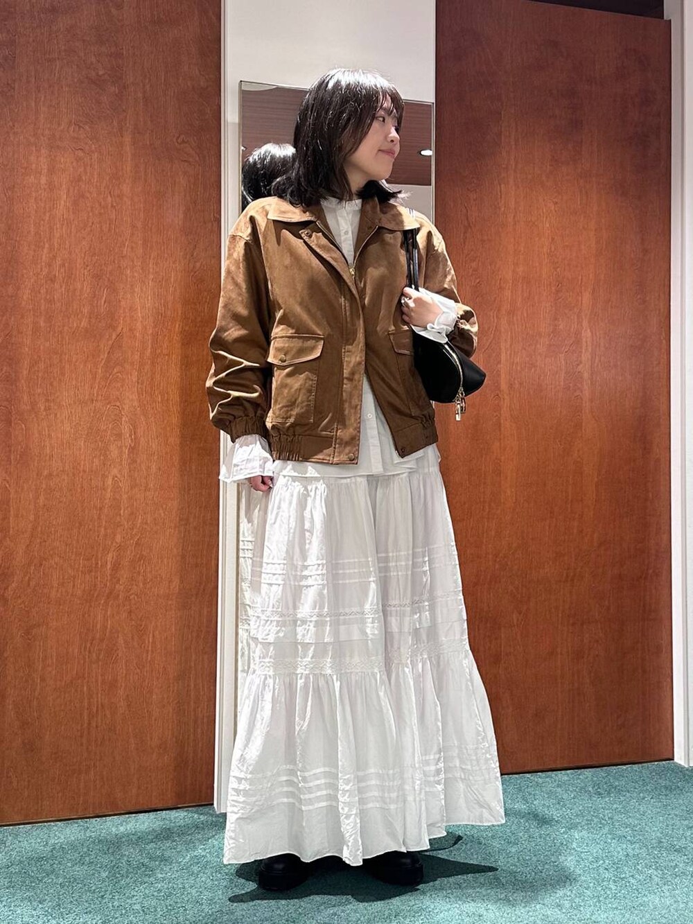 ブラック系のトートバッグ、イエロー系のブルゾン、ホワイト系のスカートを着用したレディースの秋コーディネートの2枚目の写真