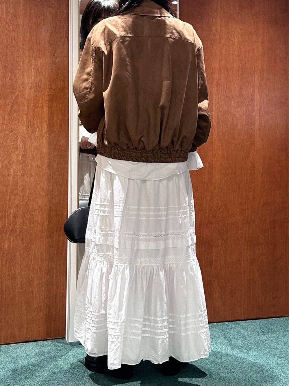 ブラック系のトートバッグ、イエロー系のブルゾン、ホワイト系のスカートを着用したレディースの秋コーディネートの4枚目の写真