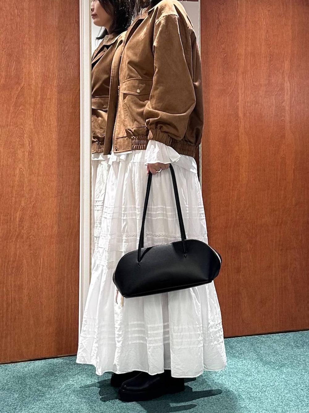 ブラック系のトートバッグ、イエロー系のブルゾン、ホワイト系のスカートを着用したレディースの秋コーディネートの3枚目の写真