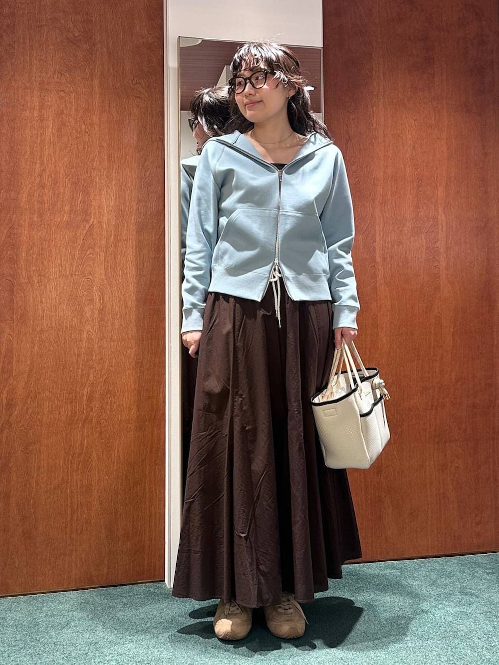 ブラック系のキャミソール、ブルー系のパーカー、ブラウン系のスカートを着用したレディースの春コーディネートの2枚目の写真