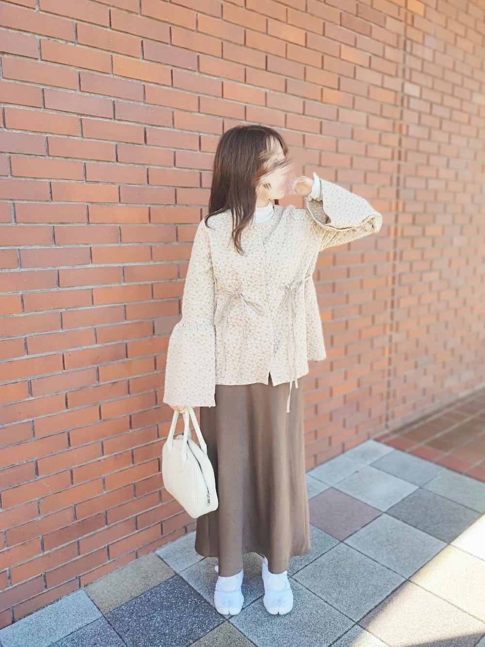 ホワイト系のハンドバッグ、ホワイト系のスニーカー、ベージュ系のシャツ/ブラウスを着用したレディースの冬コーディネートの2枚目の写真