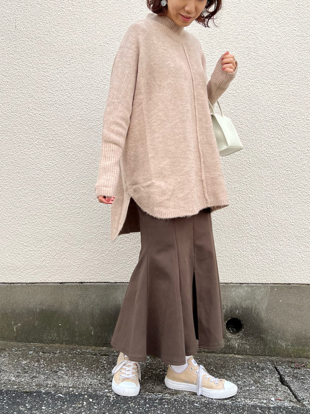 ベージュ系のニット/セーター、ベージュ系のスニーカー、ホワイト系のハンドバッグを着用したレディースの秋コーディネートの2枚目の写真