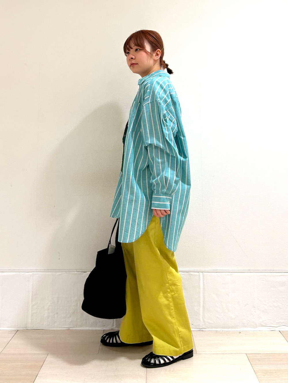 グリーン系のチュニック、ブラック系のタンクトップ、イエロー系のその他パンツを着用したレディースの春コーディネートの2枚目の写真