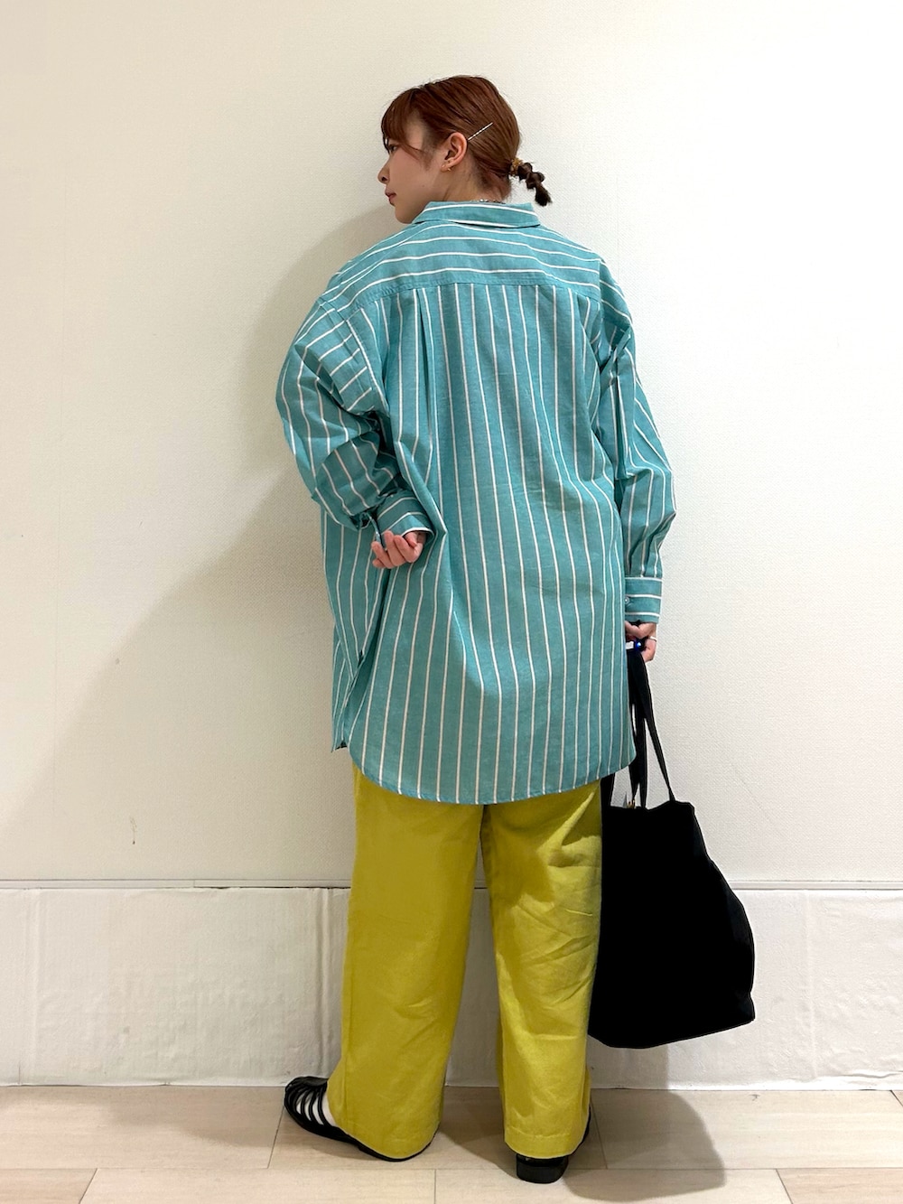 グリーン系のチュニック、ブラック系のタンクトップ、イエロー系のその他パンツを着用したレディースの春コーディネートの3枚目の写真