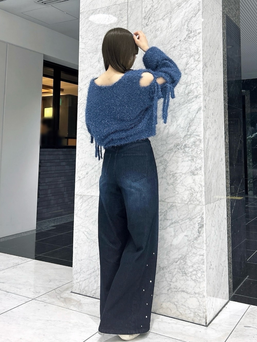 ブルー系のニット/セーター、ブルー系のデニムパンツ、ホワイト系のパンプスを着用したレディースの夏コーディネートの5枚目の写真