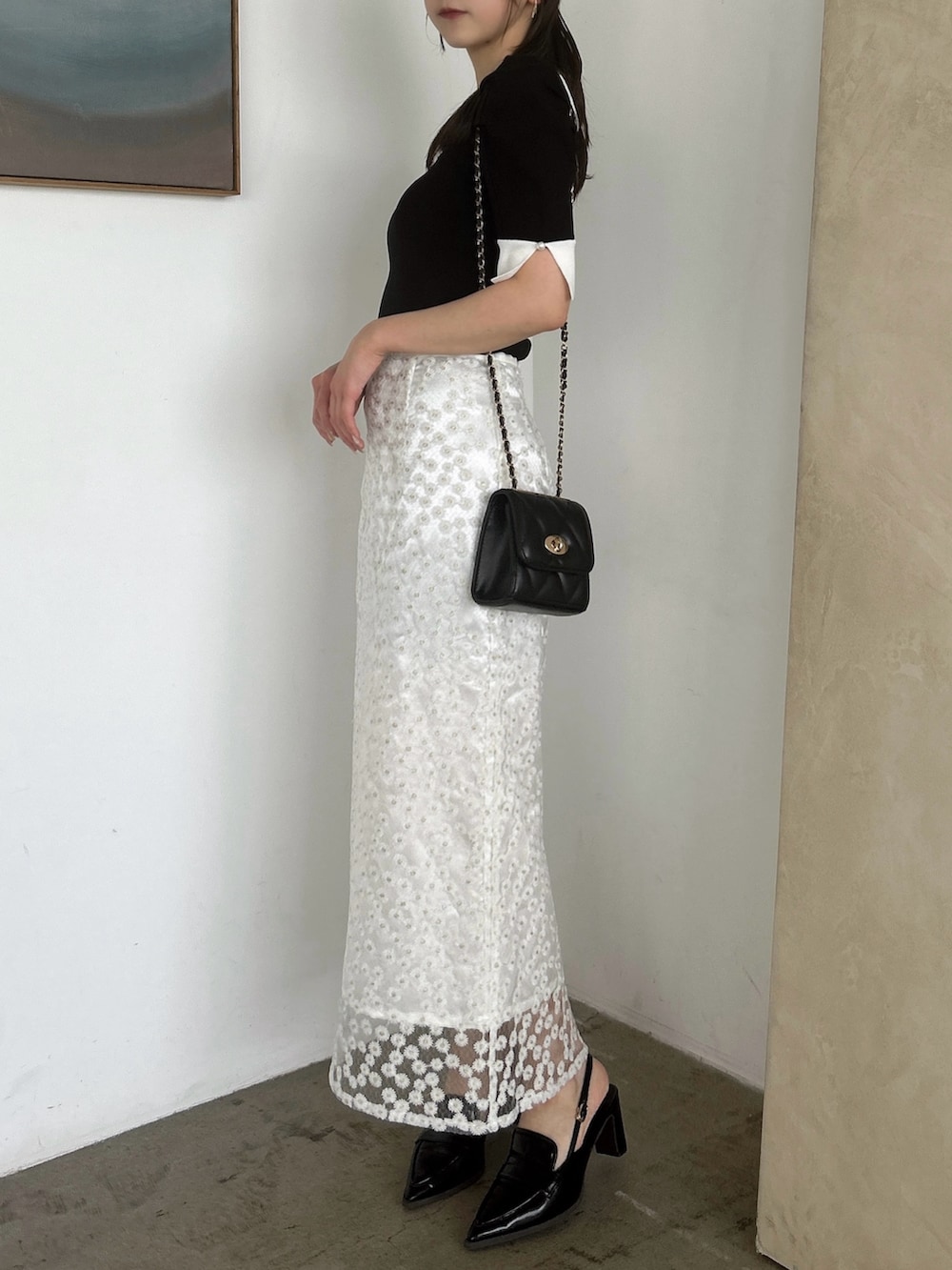 ホワイト系のスカート、ブラック系のニット/セーター、ブラック系のローファーを着用したレディースの春コーディネートの3枚目の写真