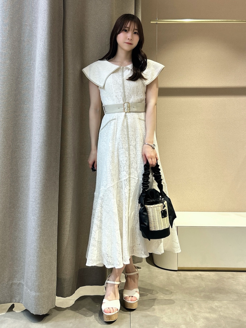 ホワイト系のワンピース、ホワイト系のサンダル、ブラック系のかごバッグを着用したレディースの夏コーディネートの2枚目の写真