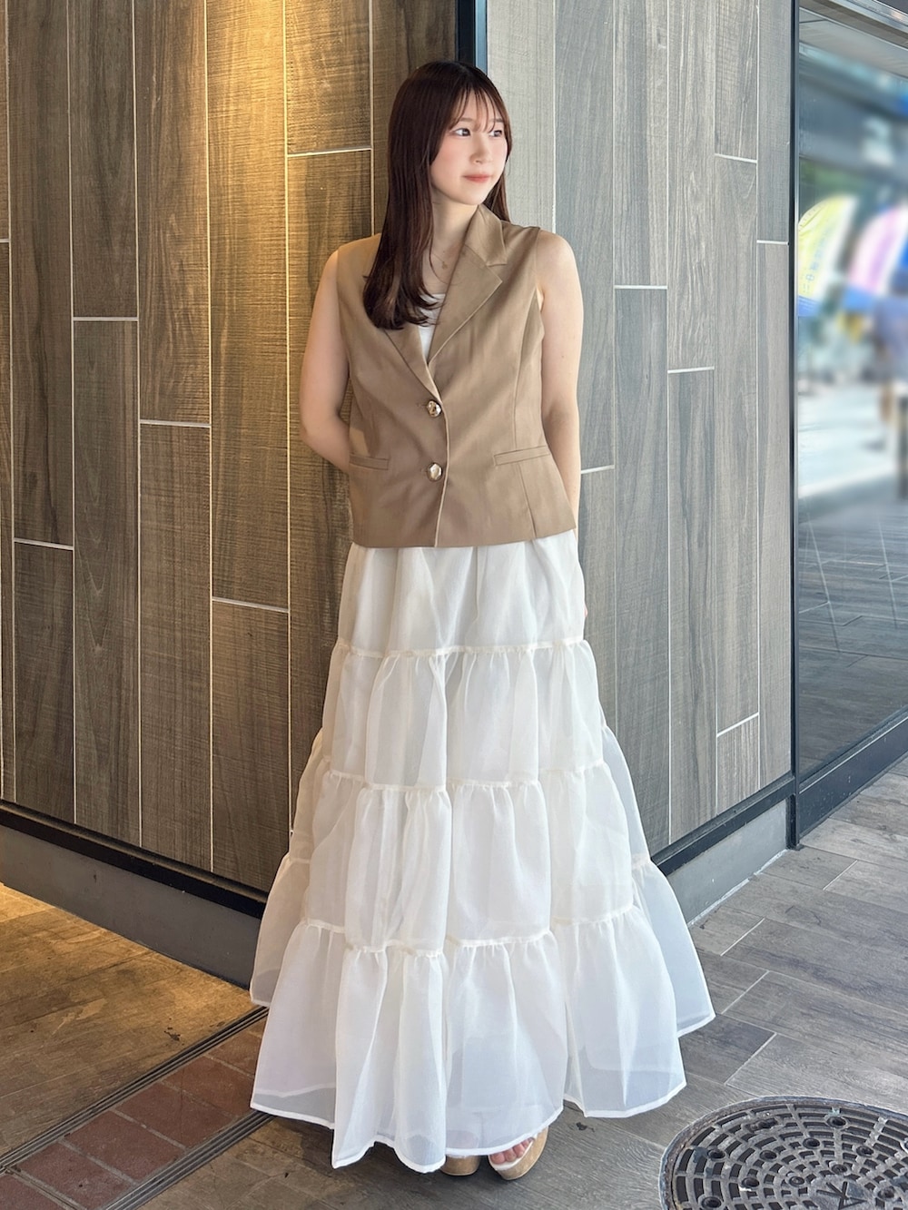 ブラウン系のベスト、ホワイト系のTシャツ/カットソー、ベージュ系のスカートを着用したレディースの秋コーディネートの3枚目の写真