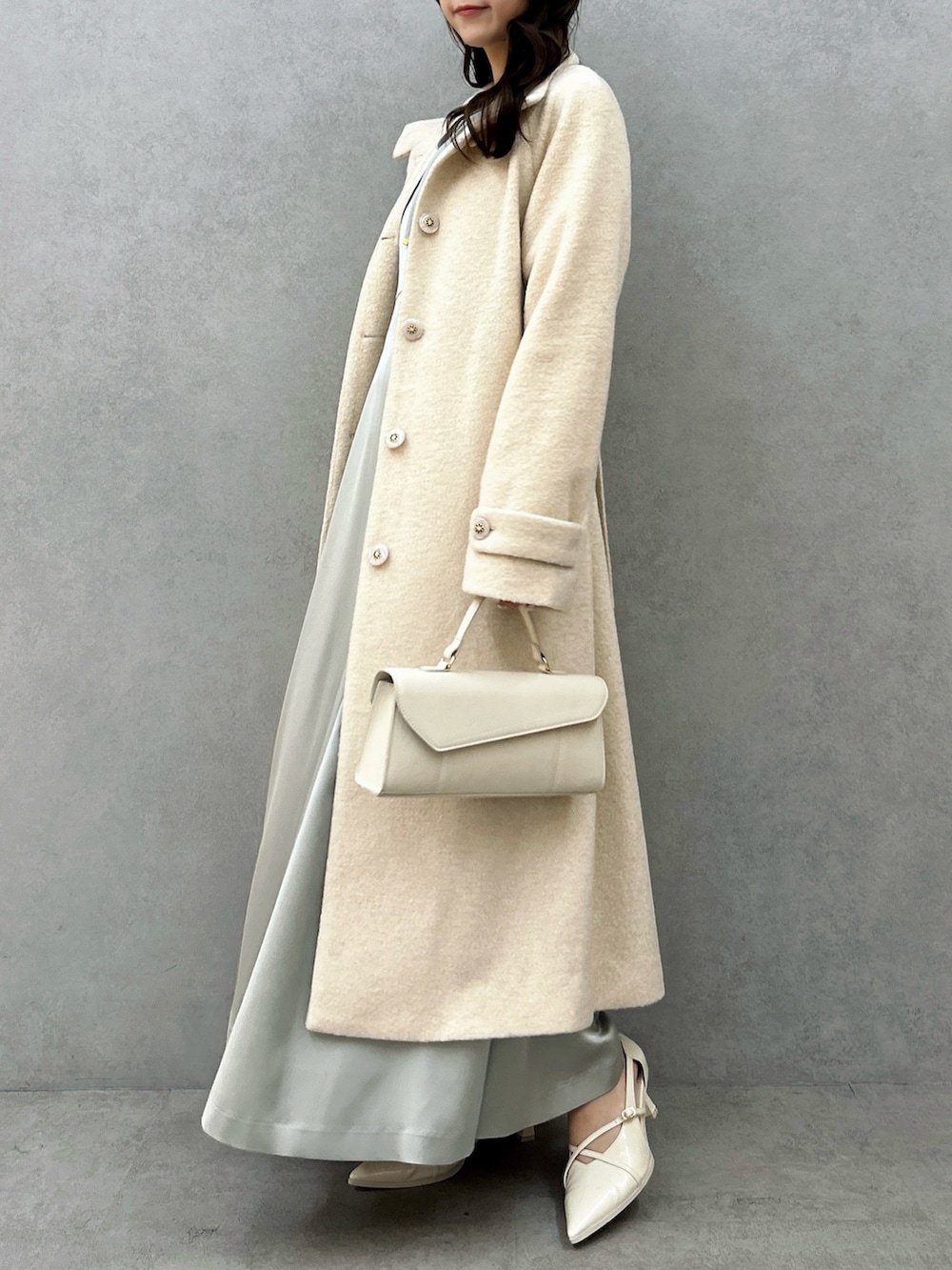 ホワイト系のその他アウター、グリーン系のドレス、ホワイト系のパンプスを着用したレディースの冬コーディネートの3枚目の写真