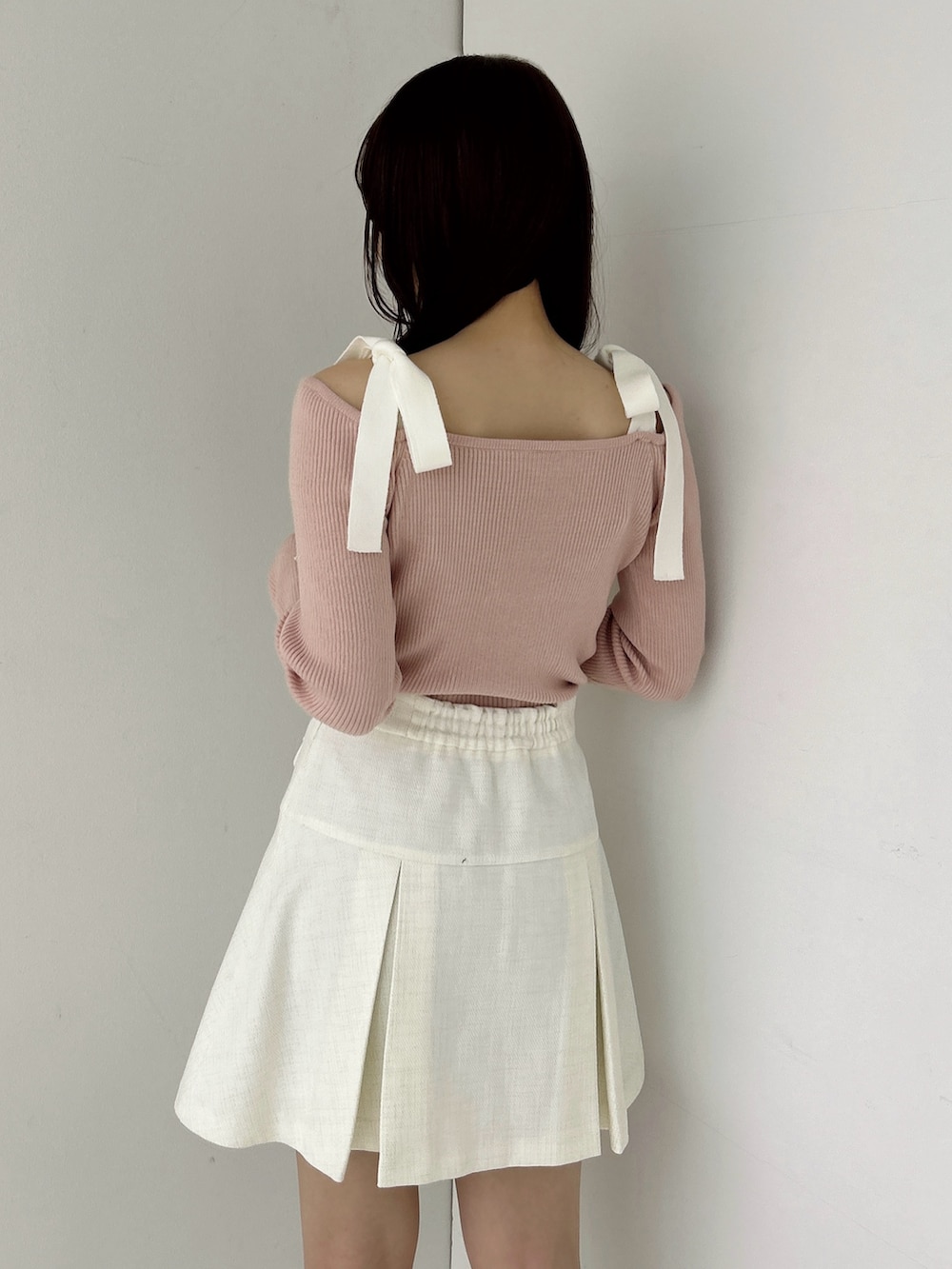 ピンク系のニット/セーター、ホワイト系のスカート、ホワイト系のブーツを着用したレディースの冬コーディネートの10枚目の写真