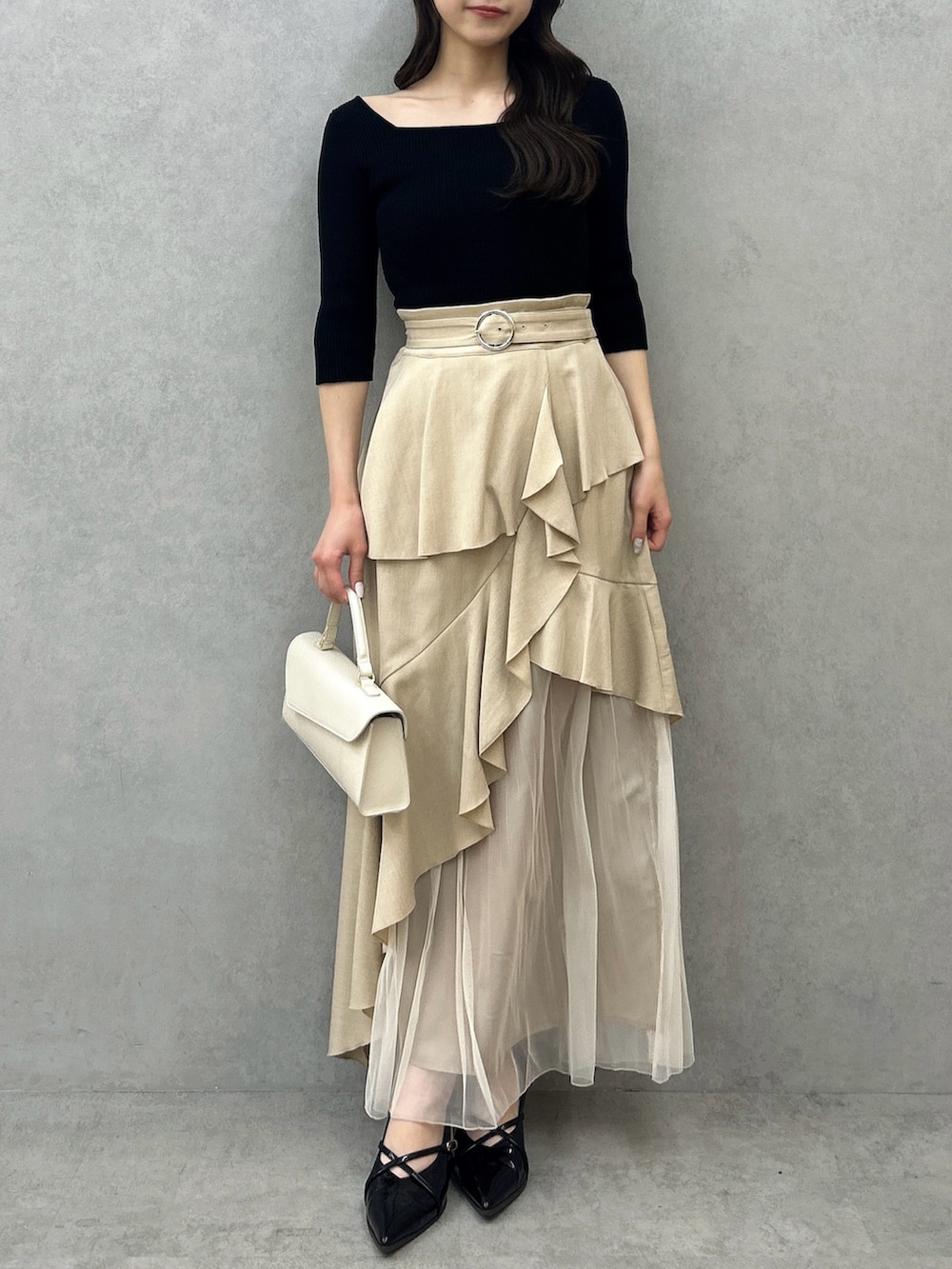 ブラック系のニット/セーター、ベージュ系のスカート、ブラック系のパンプスを着用したレディースの冬コーディネートの2枚目の写真