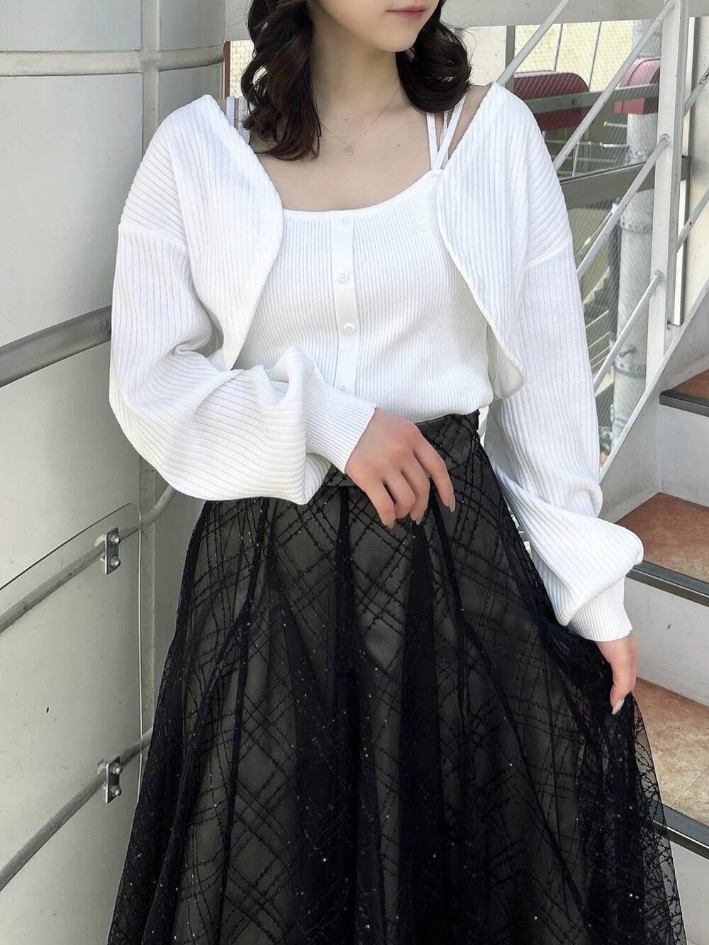 ホワイト系のアンサンブル、ブラック系のスカート、ブラック系のパンプスを着用したレディースの春コーディネートの6枚目の写真