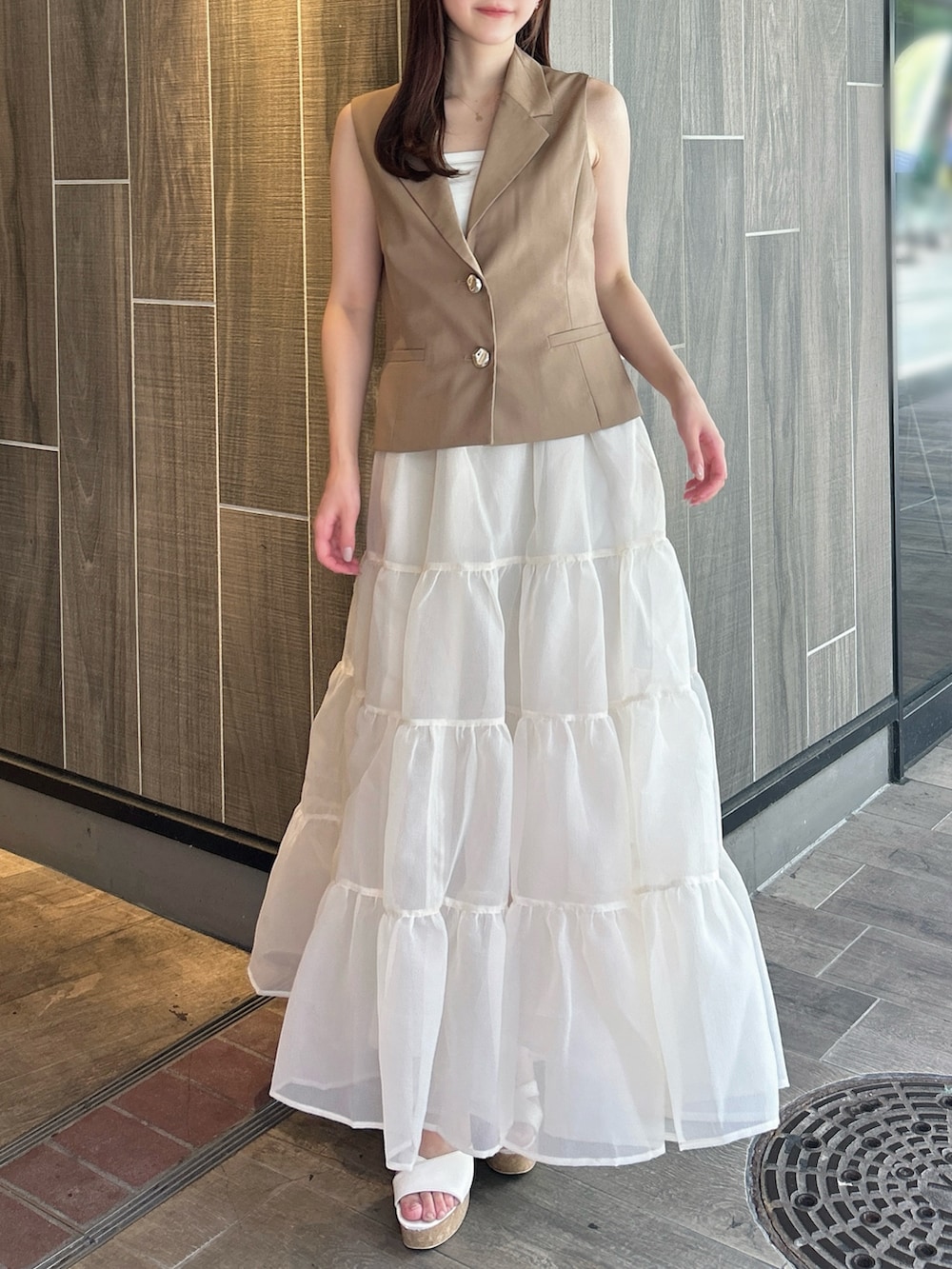 ブラウン系のベスト、ホワイト系のTシャツ/カットソー、ベージュ系のスカートを着用したレディースの秋コーディネートの4枚目の写真