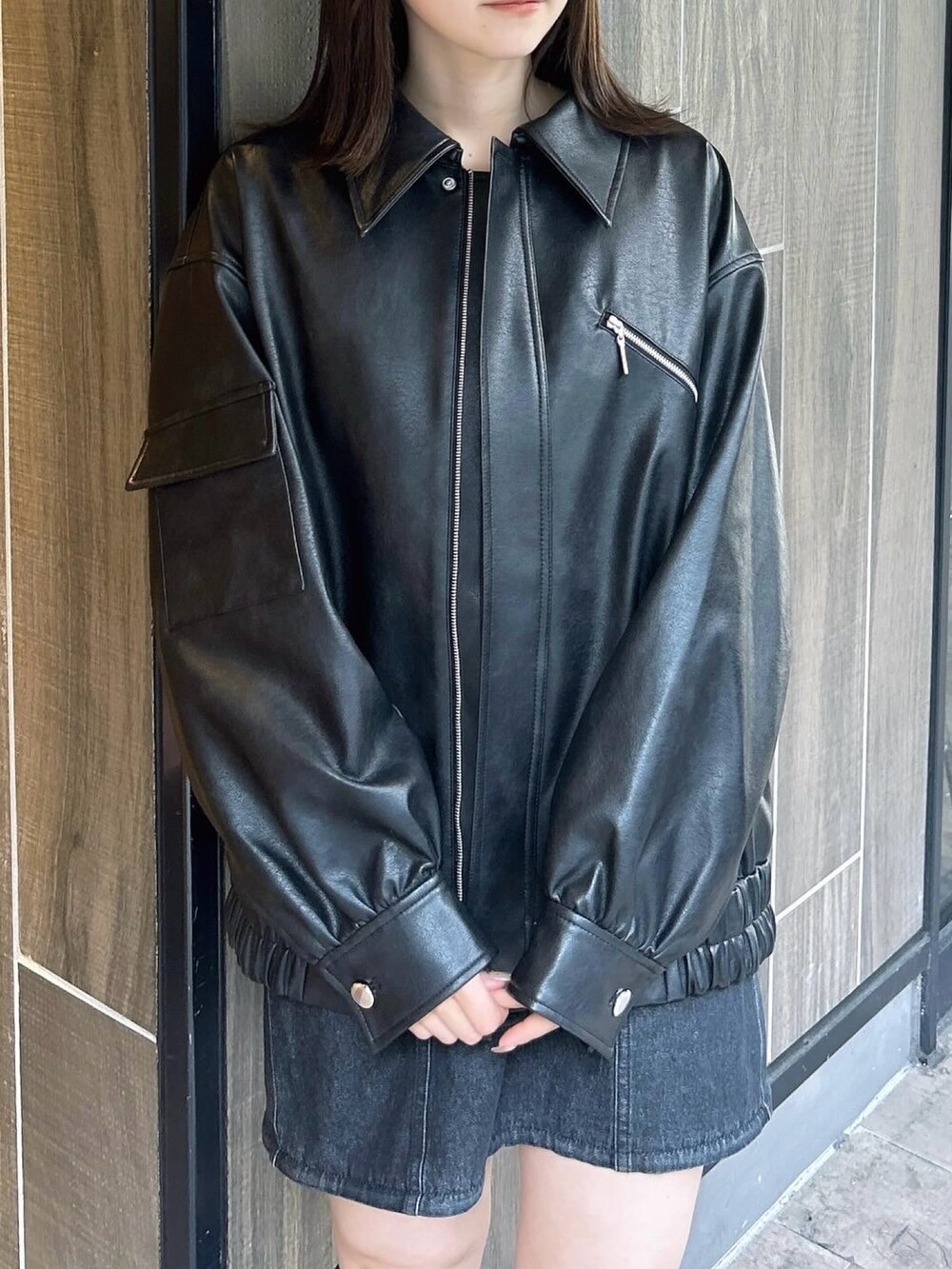 ブラック系のブルゾン、ブラック系のワンピース、ブラック系のブーツを着用したレディースの春コーディネートの5枚目の写真