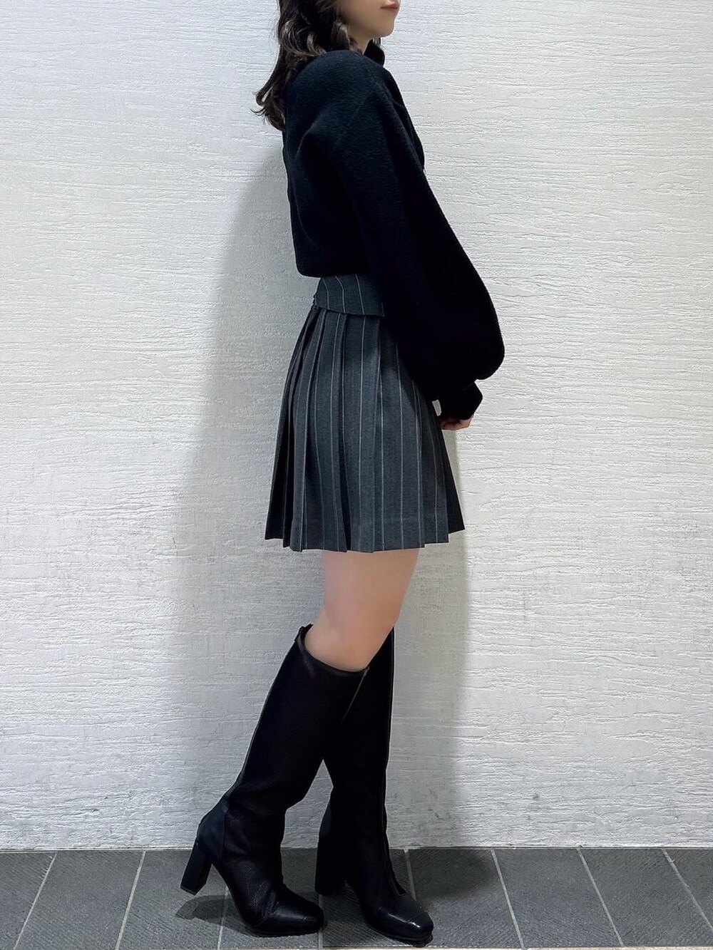 ブラック系のニット/セーター、グレー系のスカート、ブラック系のブーツを着用したレディースの春コーディネートの3枚目の写真