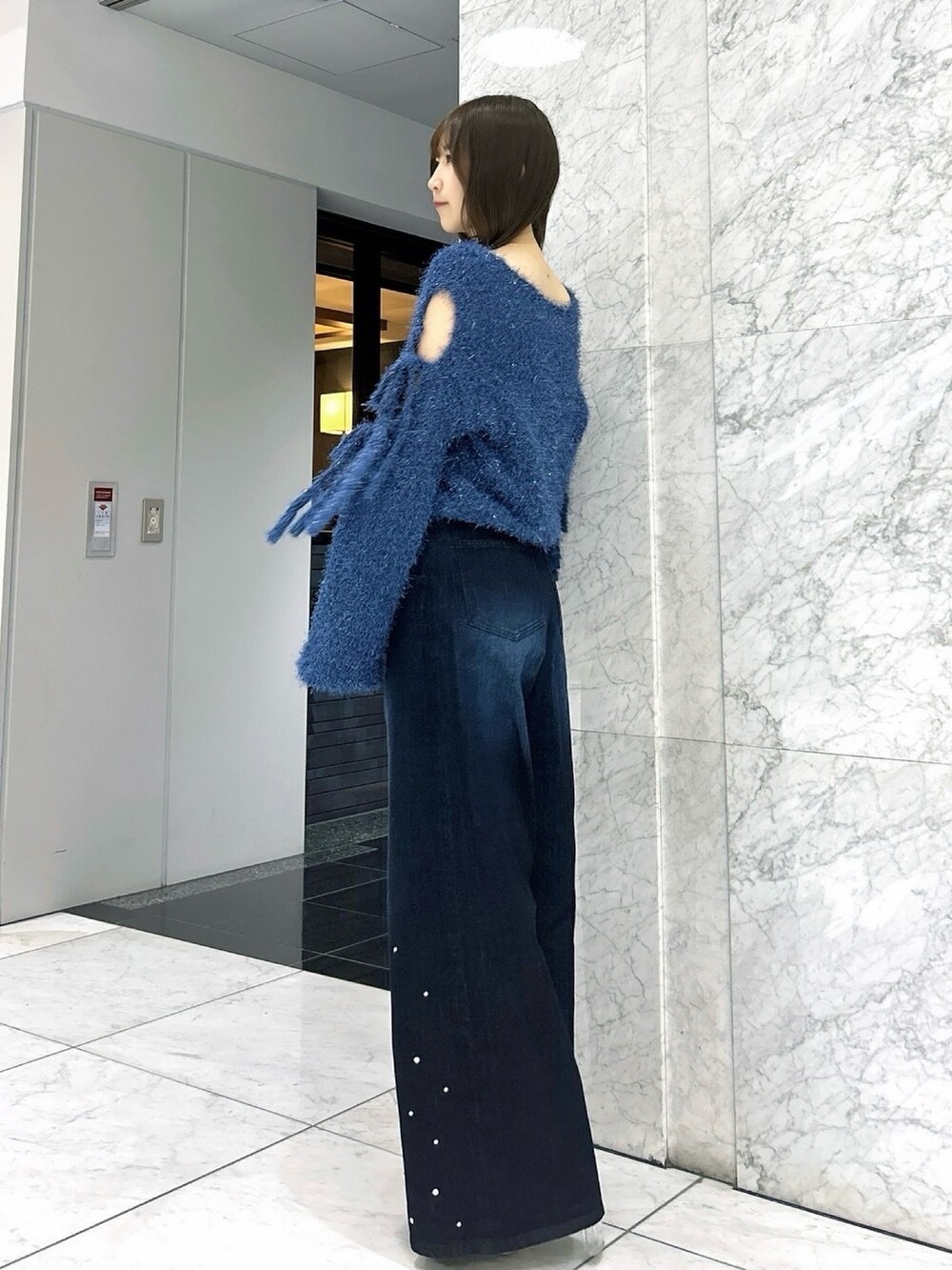 ブルー系のニット/セーター、ブルー系のデニムパンツ、ホワイト系のパンプスを着用したレディースの夏コーディネートの3枚目の写真