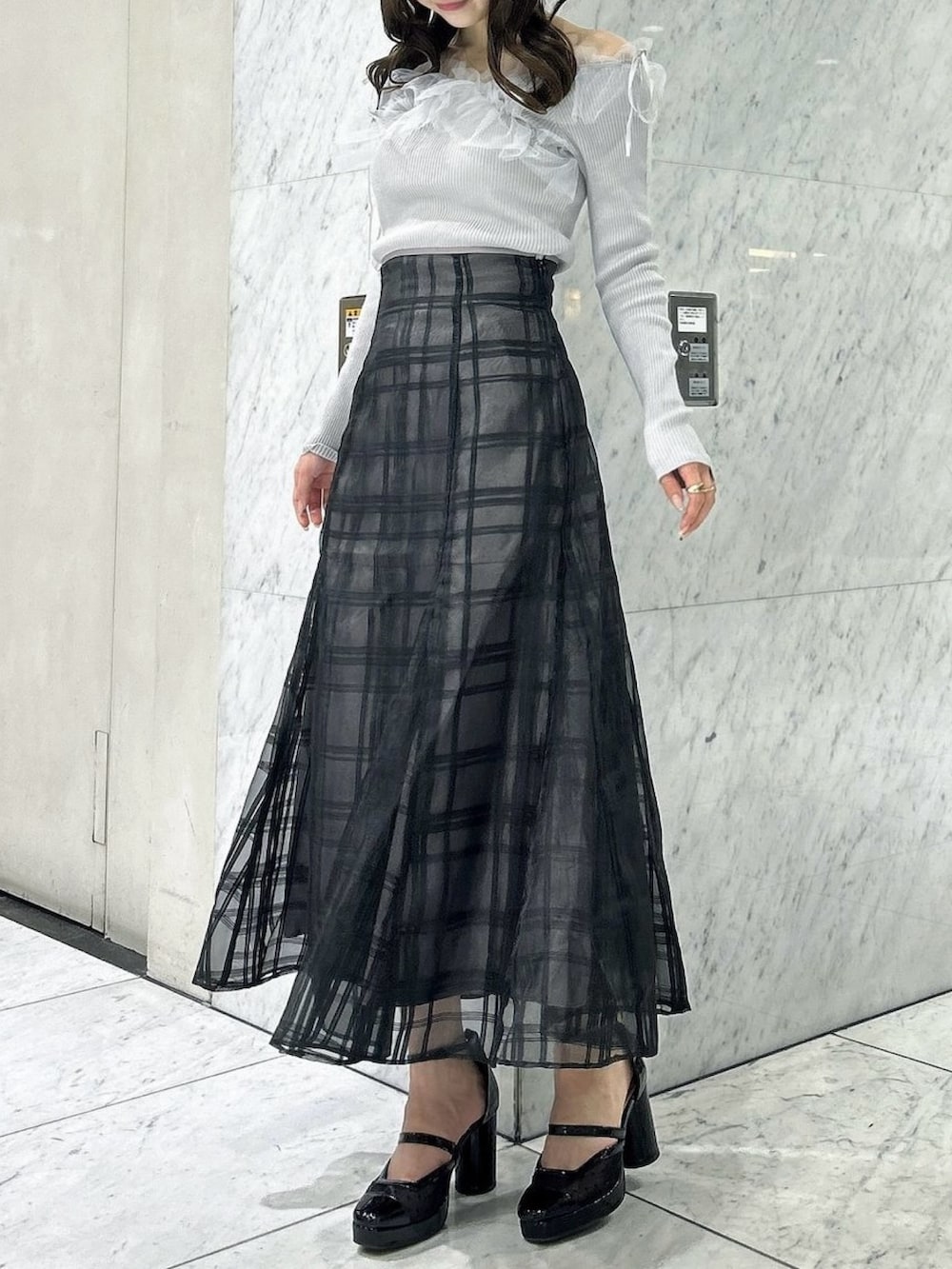 ブラック系のスカート、ブラック系のパンプス、グレー系のニット/セーターを着用したレディースの秋コーディネートの2枚目の写真